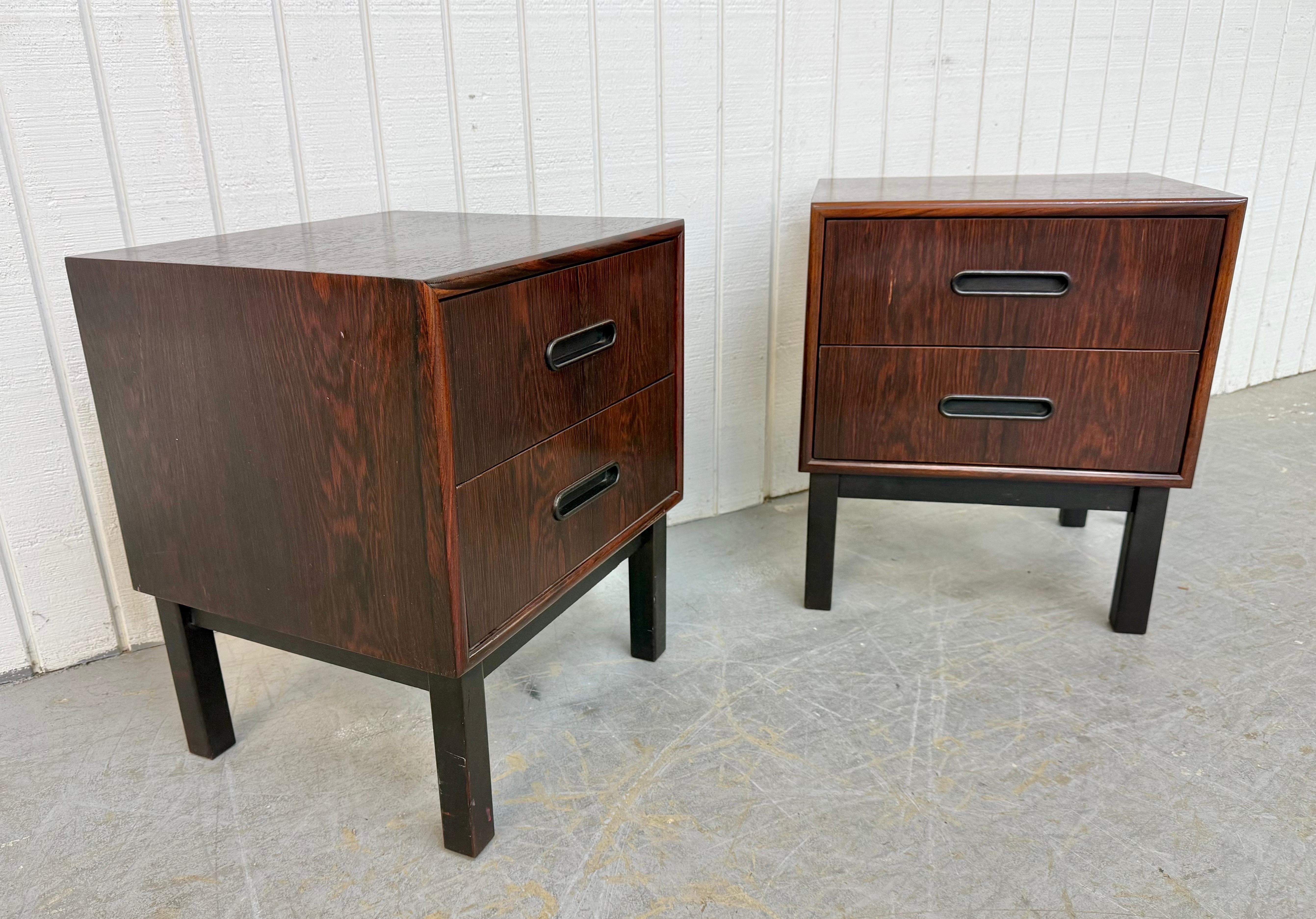Questo annuncio si riferisce a una coppia di comodini in legno di palissandro della modernità danese del metà del secolo. Caratterizzato da un design a cubo dalla linea retta, due cassetti con tiretti ovali incassati, gambe moderne verniciate di
