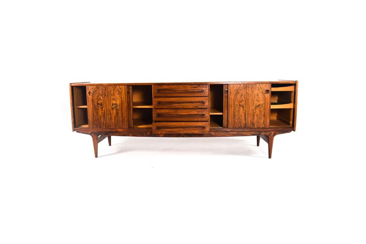 A very well made danish rosewood sideboard. The cabinet has four drawers in center and sliding doors on either side. Oak interior with adjustable shelves and drawers, recessed handles and cutlery drawer. With carved wood door handles, and plenty of