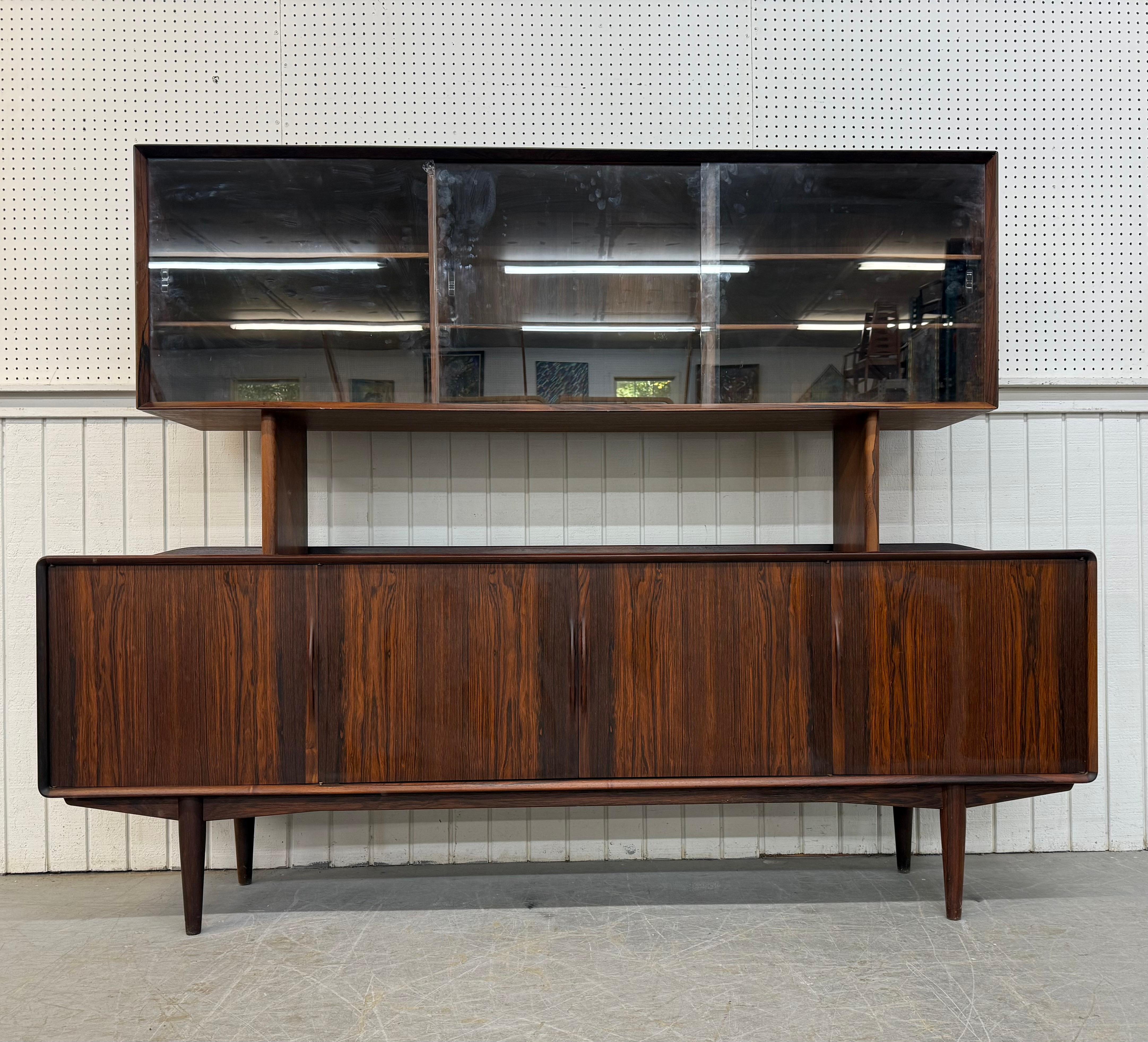 Questo annuncio si riferisce a una rara credenza danese moderna di metà secolo in legno di palissandro. Caratterizzato da un design lineare, il piano della conigliera con ante scorrevoli in vetro che rivelano lo spazio per gli scaffali, le ante alla