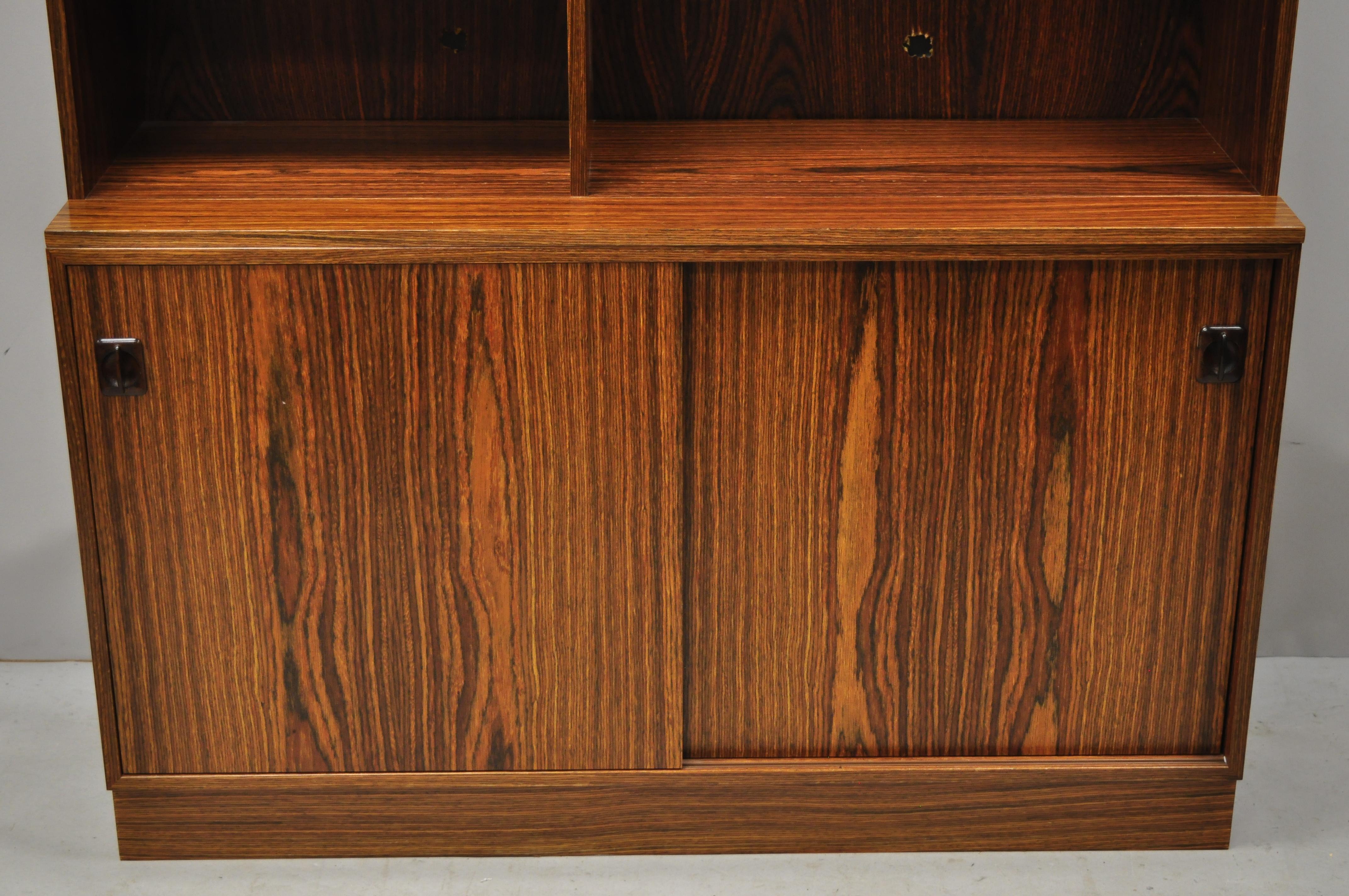 Midcentury Danish modern rosewood sliding door credenza cabinet bookcase hutch. Item features a nice smaller size, sculpted rosewood pulls, 2 sliding doors, beautiful wood grain, 2 part construction, 4 adjustable shelves, clean modernist lines,