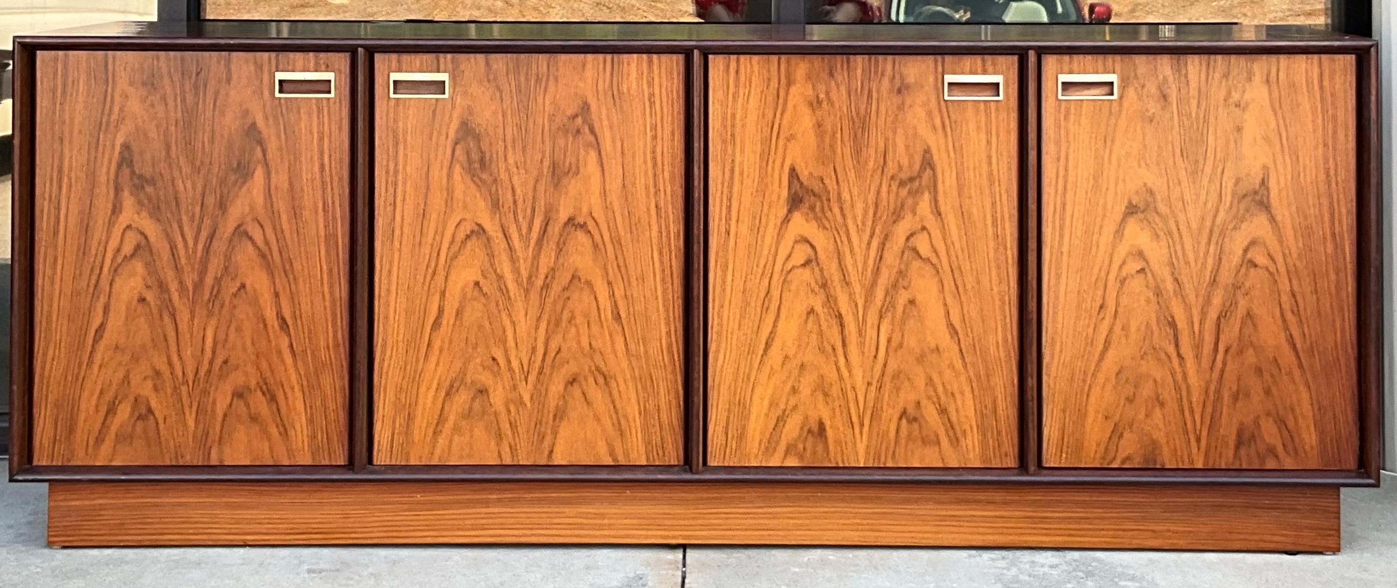 This is a versatile piece! From dining to media, it could work any where! This is a midcentury Danish modern credenza. It is a rosewood veneer with brass hardware. It is in very good condition, and the interior provides a substantial amount of