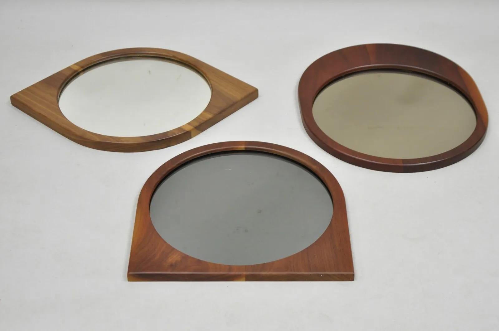 Mid Century Modern Danish Style Sculpted Teak Wood Mirrors - 3 pc Set. Set includes all three mirrors. (1) cat eye mirror with clear mirror, (1) flat bottom with gray smoked mirror, (1) rounded bottom with amber colored mirror, all with beautiful