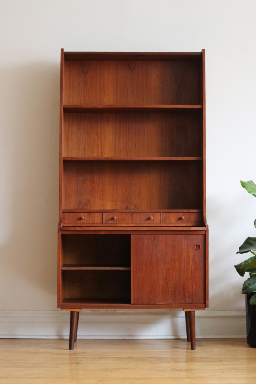 Midcentury Danish modern teakwood shelving unit.
Just imported from Copenhagen.
Hidden shelf pulls out to create a desk or extra work surface.
Top shelves are adjustable.
Three small dovetailed drawers.
Beautiful teak woodgrain.
Great for