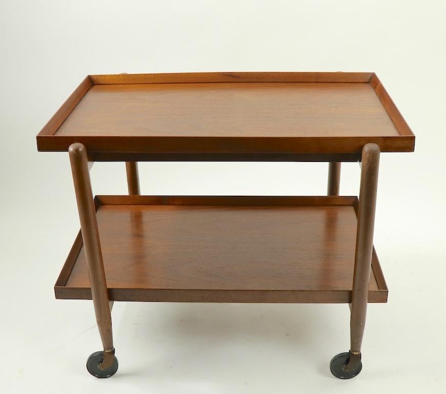 Classic Danish modern serving cart designed by Poul Huundevad. The cart features two rectangular shelves, the lower shelf is removable and can be positioned next to the top shelf, creating a larger serving surface. Dimensions closed 29.5 W x 20.5 D