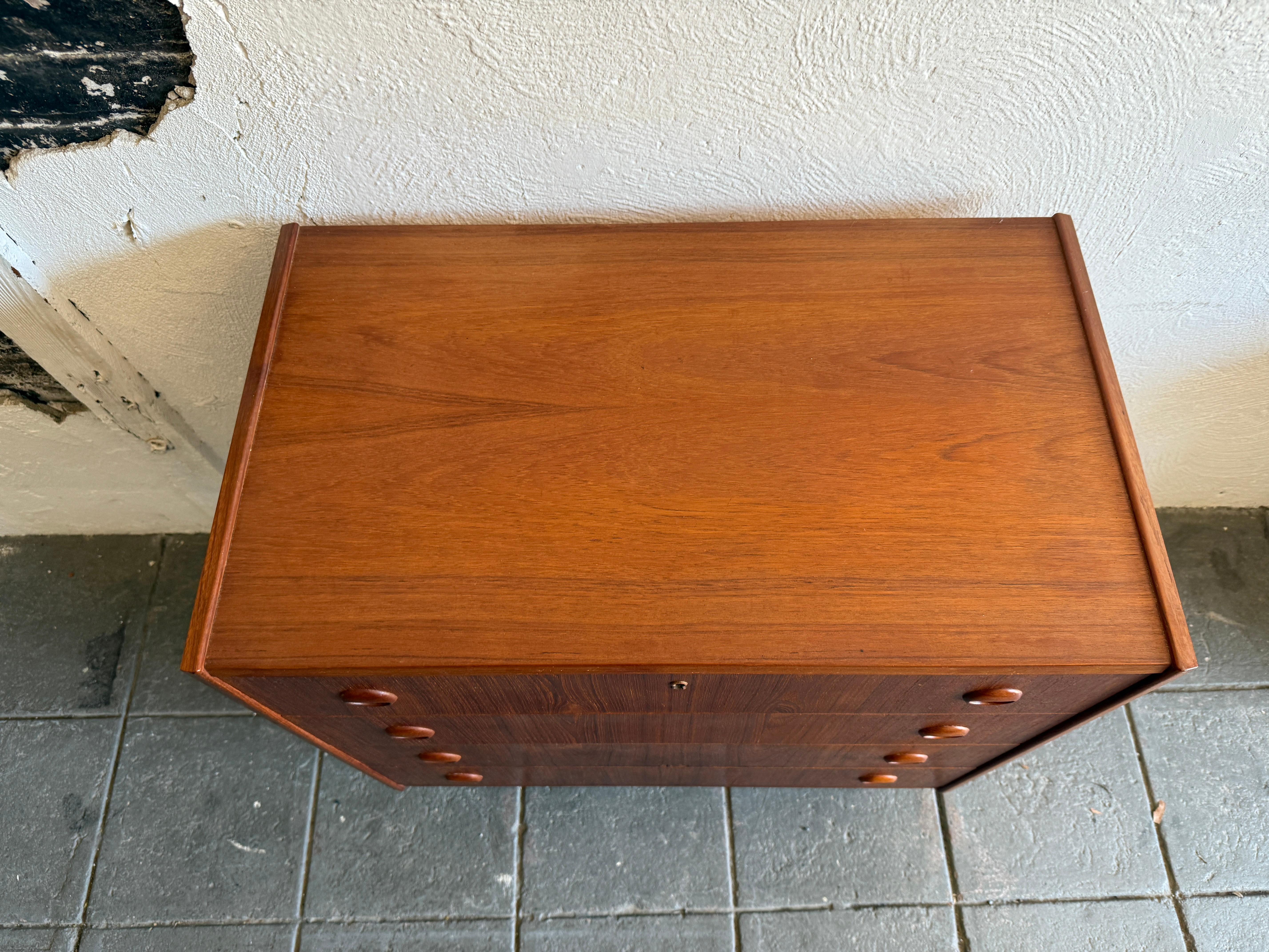 cómoda baja de 4 cajones de madera de teca de mediados del siglo xx sobre patas Carpintería en venta
