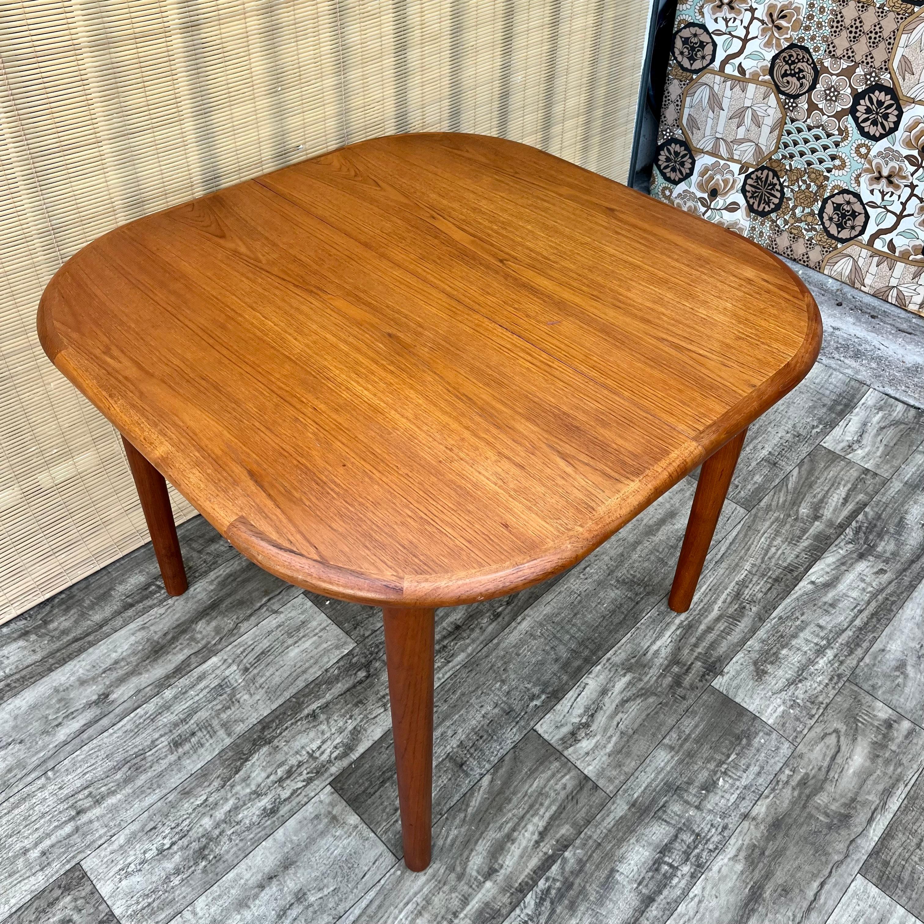 Vintage Mid Century Danish Modern Style Extendable Dining Table by Diethelm Scanstyle.  Circa 1980s 
Features a sleek Mid Century Modern Scandinavian design, rounded edges with solid teak trims, a wonderful teak wood grain, and two folded leaves
