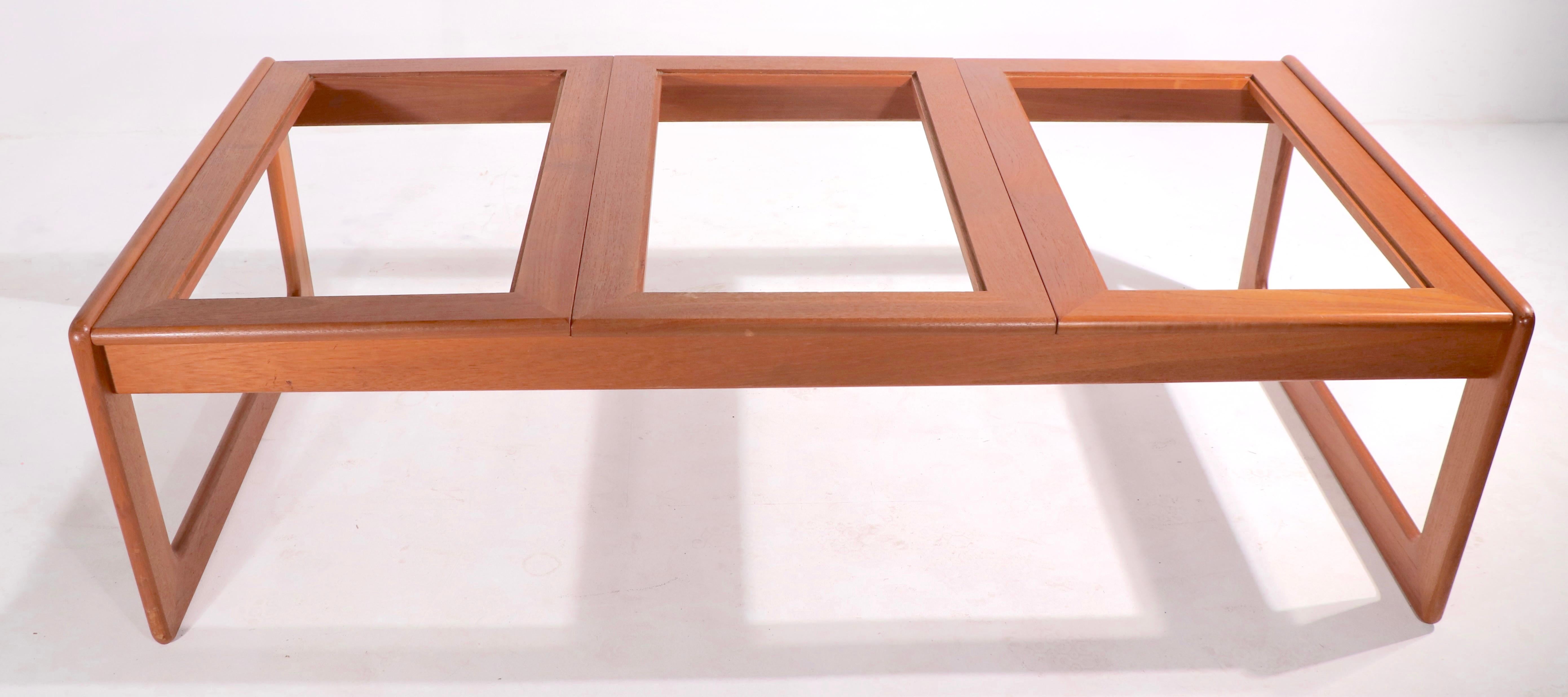 Table basse grillagée de taille inhabituelle fabriquée au Danemark par Komfort. Cet exemple a un cadre en teck massif, avec trois panneaux en verre teinté insérés dans la partie supérieure. La plupart des tables basses à grille Kormfort n'ont que
