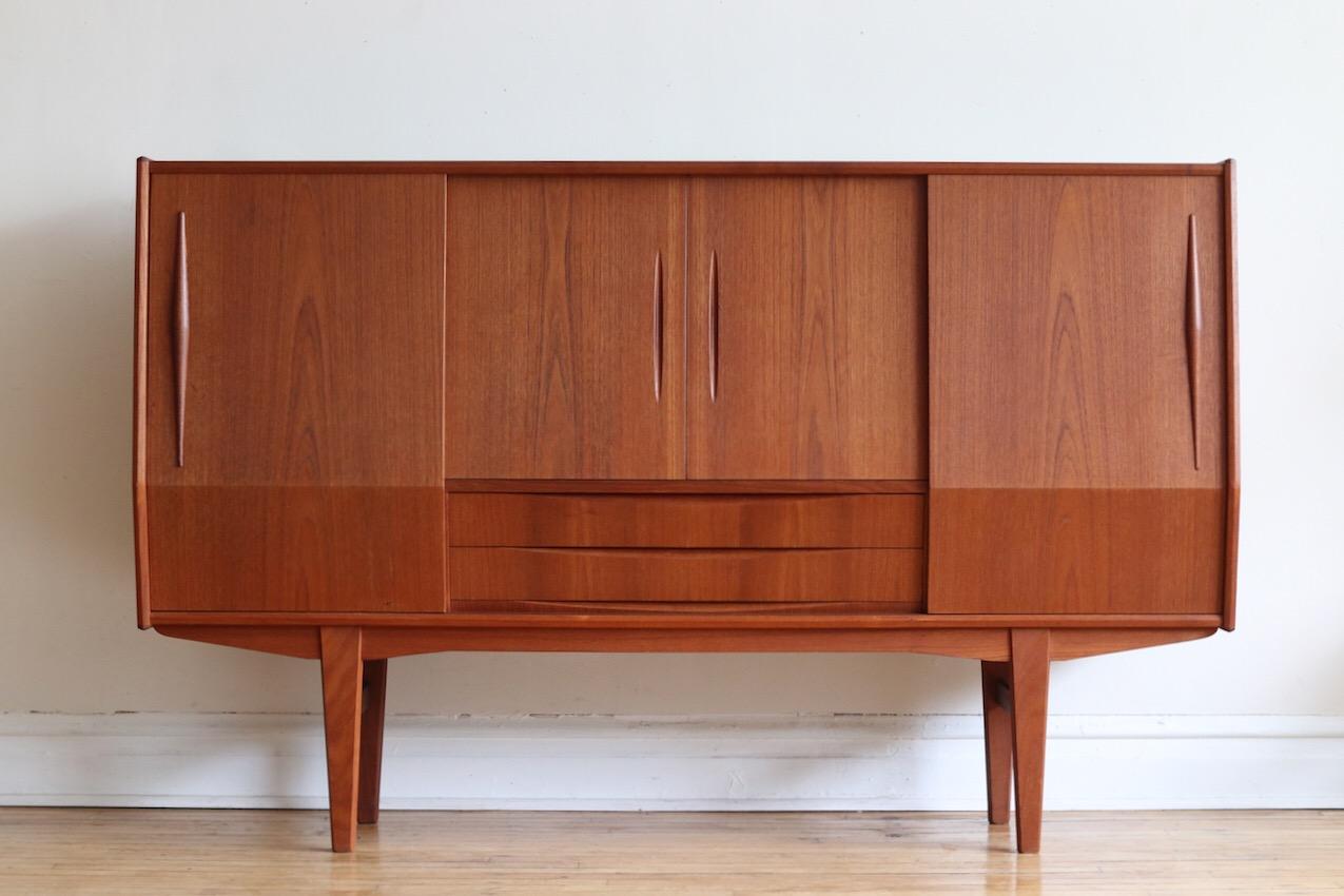 Mid-Century Modern Danish tall teakwood credenza.
Just imported from Copenhagen.
Center compartment features a rosewood bar, brass risers and an etched mirror!
Six dovetailed drawers total.
Sliding doors; adjustable shelving in left and right