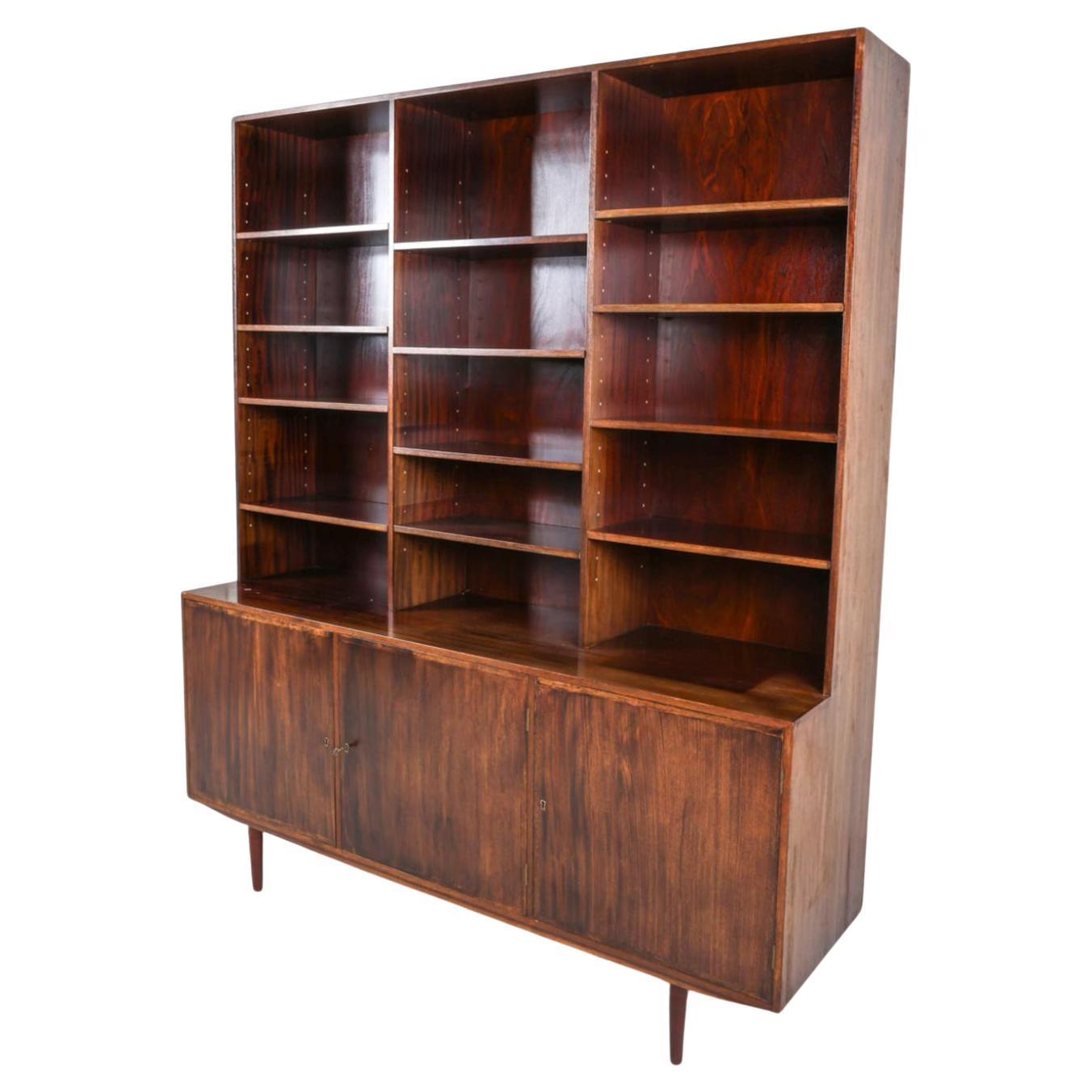 Credenza in palissandro alta e larga in stile danese del metà secolo, con libreria Key. Credenza inferiore a (3) ante con (4) cassetti, l'altro lato è dotato di ripiani regolabili. La libreria pensile alta in alto ha tutti i ripiani regolabili (12).