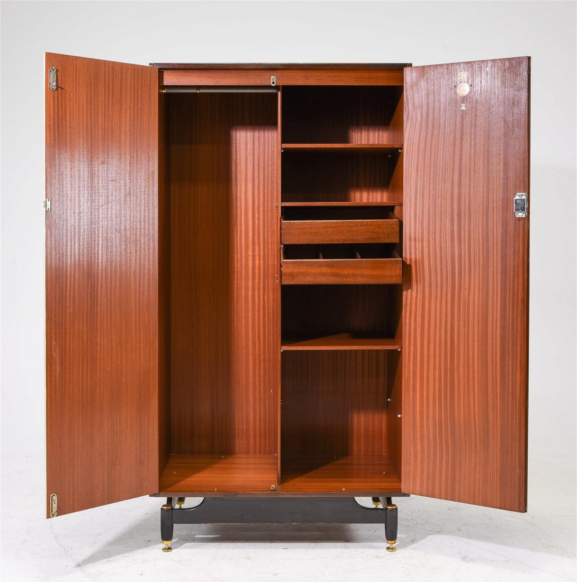 Mid-century modern teak high wardrobe dresser. Has 2 sliding front doors has multiple interior shelf and 2 drawers with dovetail joints. Left side is open with hang bar for clothing. Sits on black lacquered base with brass feet. Stamped on the door