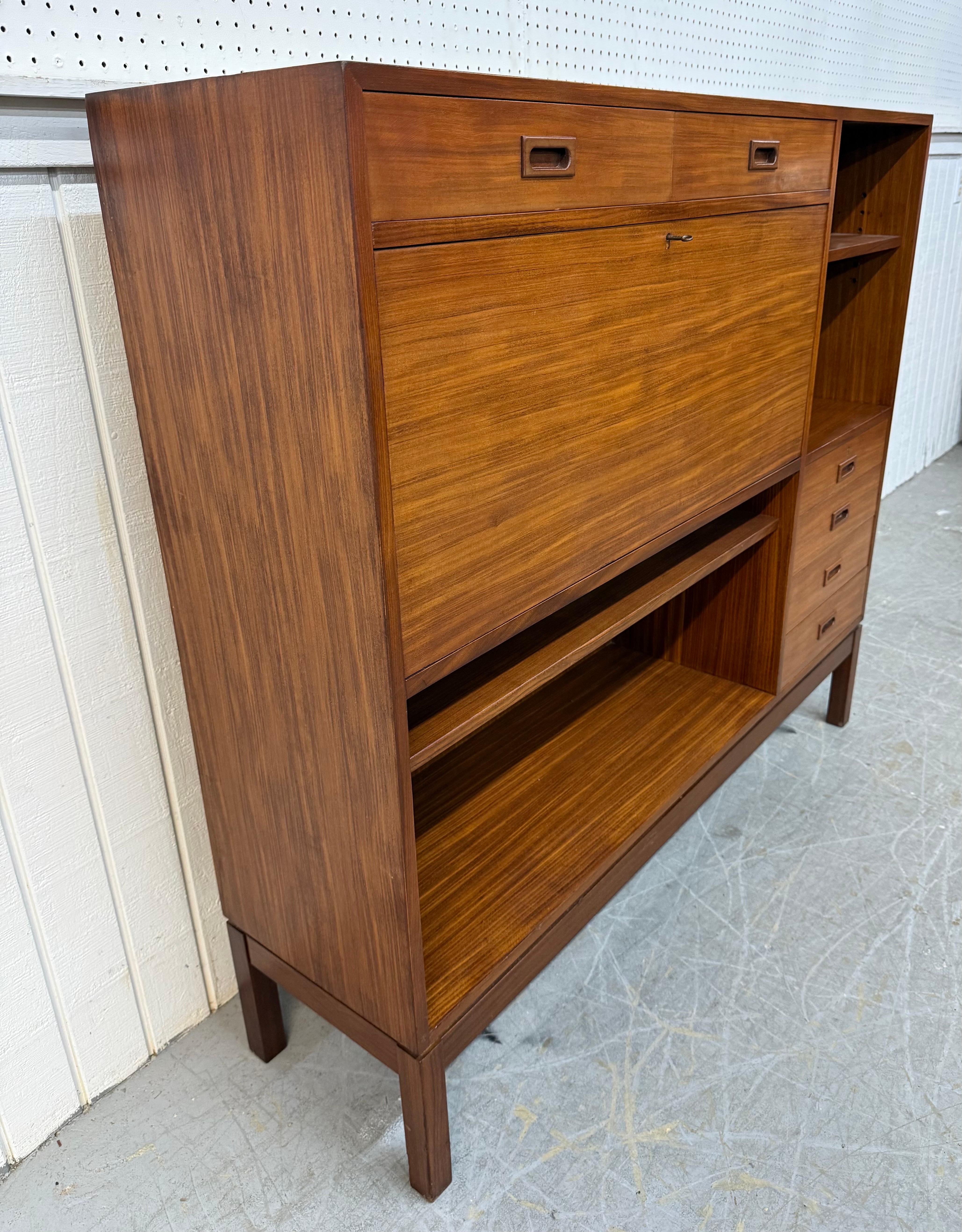 This listing is for a Mid-Century Danish Modern Teak Bar Cabinet. Featuring a straight line design, six drawers for storage, two shelves for storage, drop down bar cabinet door, modern legs, and a beautiful teak finish. This is an exceptional