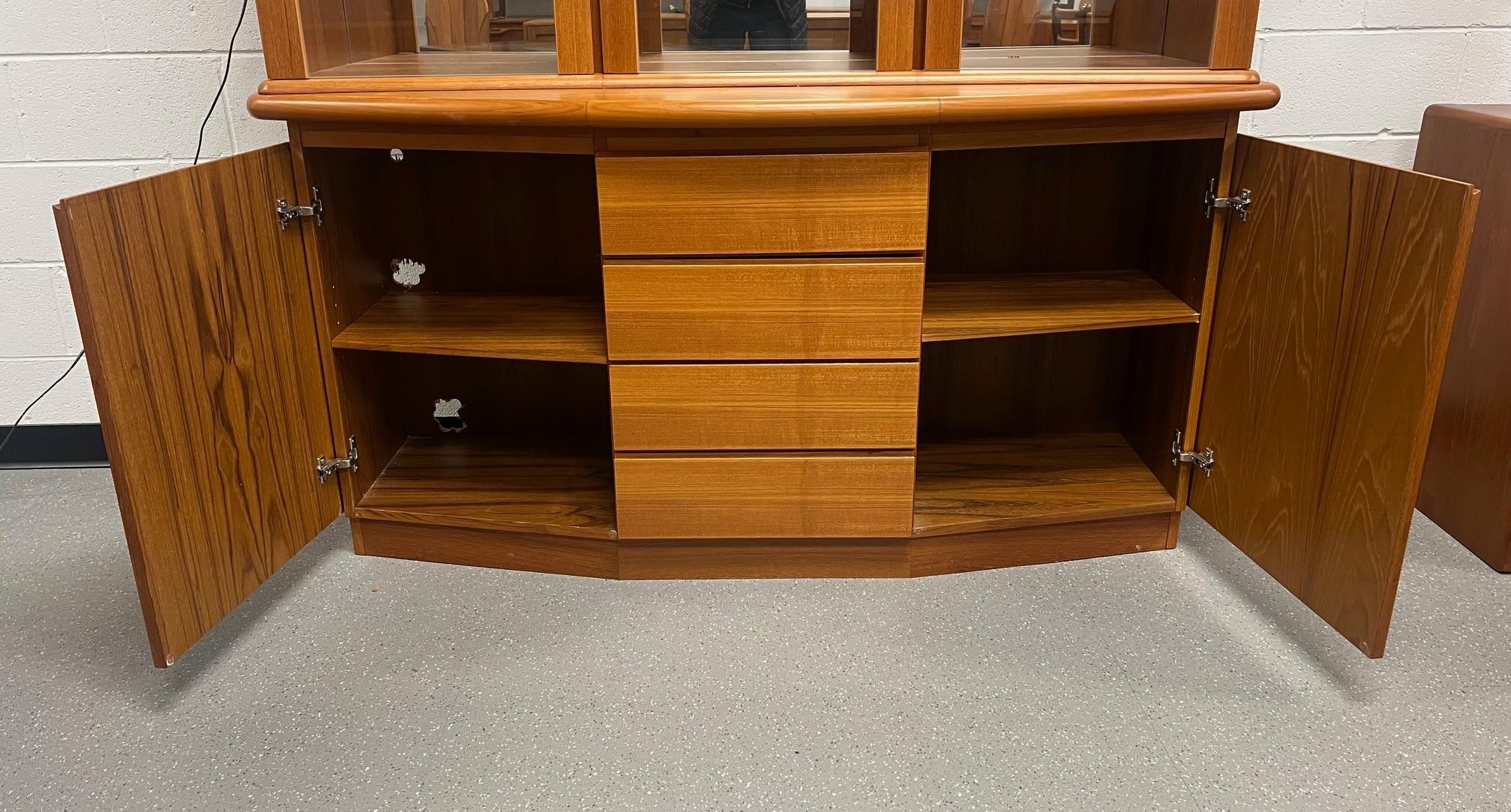 Gorgeous Danish Modern teak buffet with hutch. Curved top contrasted by bow front bottom.

Featuring adjustable glass shelves at the top. Adjustable wood shelves at the bottom and four clean drawers. Someone cut several holes into the back of the