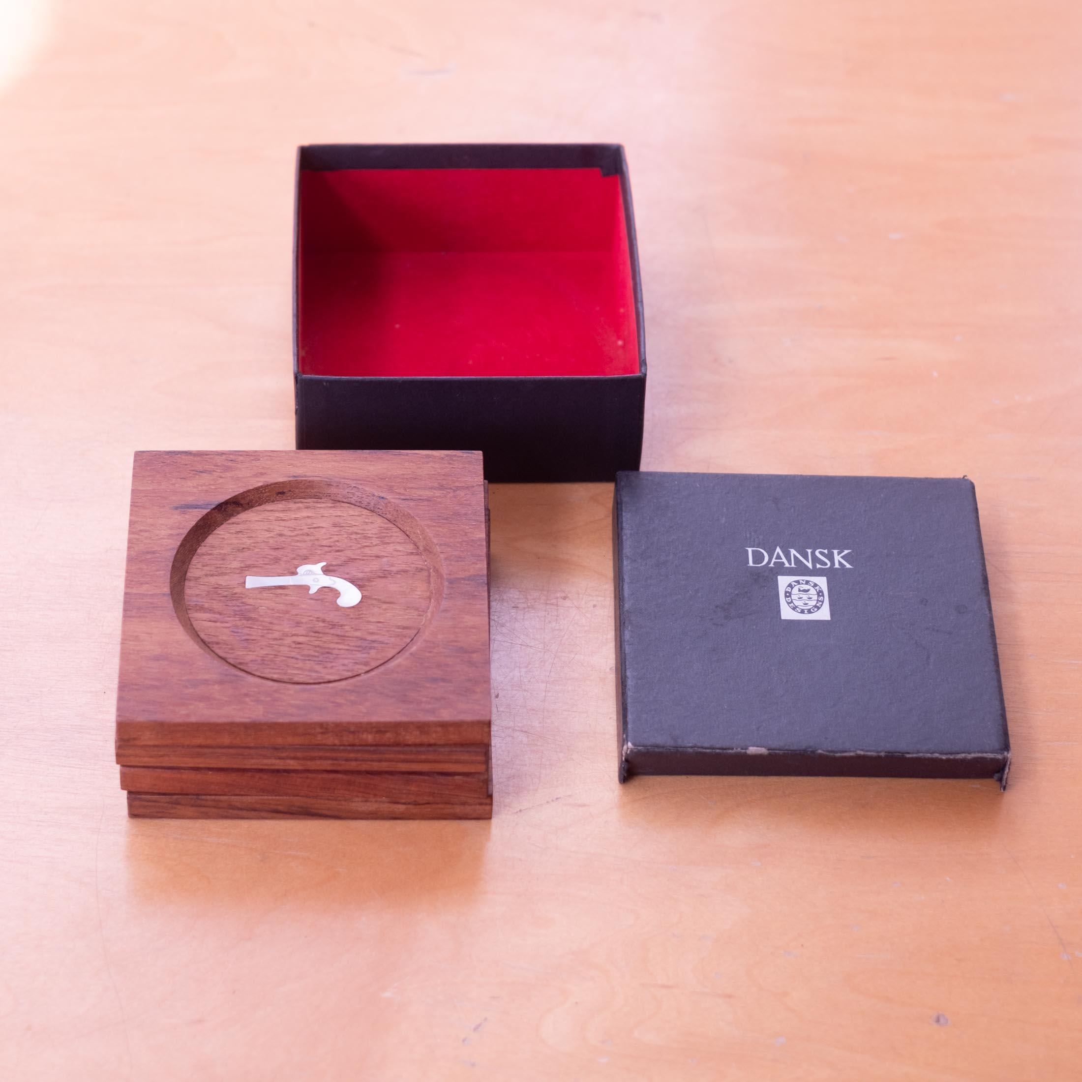 Set de sous-verres en teck du milieu du siècle dernier par Jens H. Quistgaard pour Dansk. Comprend quatre sous-verres dans la boîte d'origine. Teck massif avec incrustation de pistolet à silex en acier inoxydable. Danemark, années 1950.