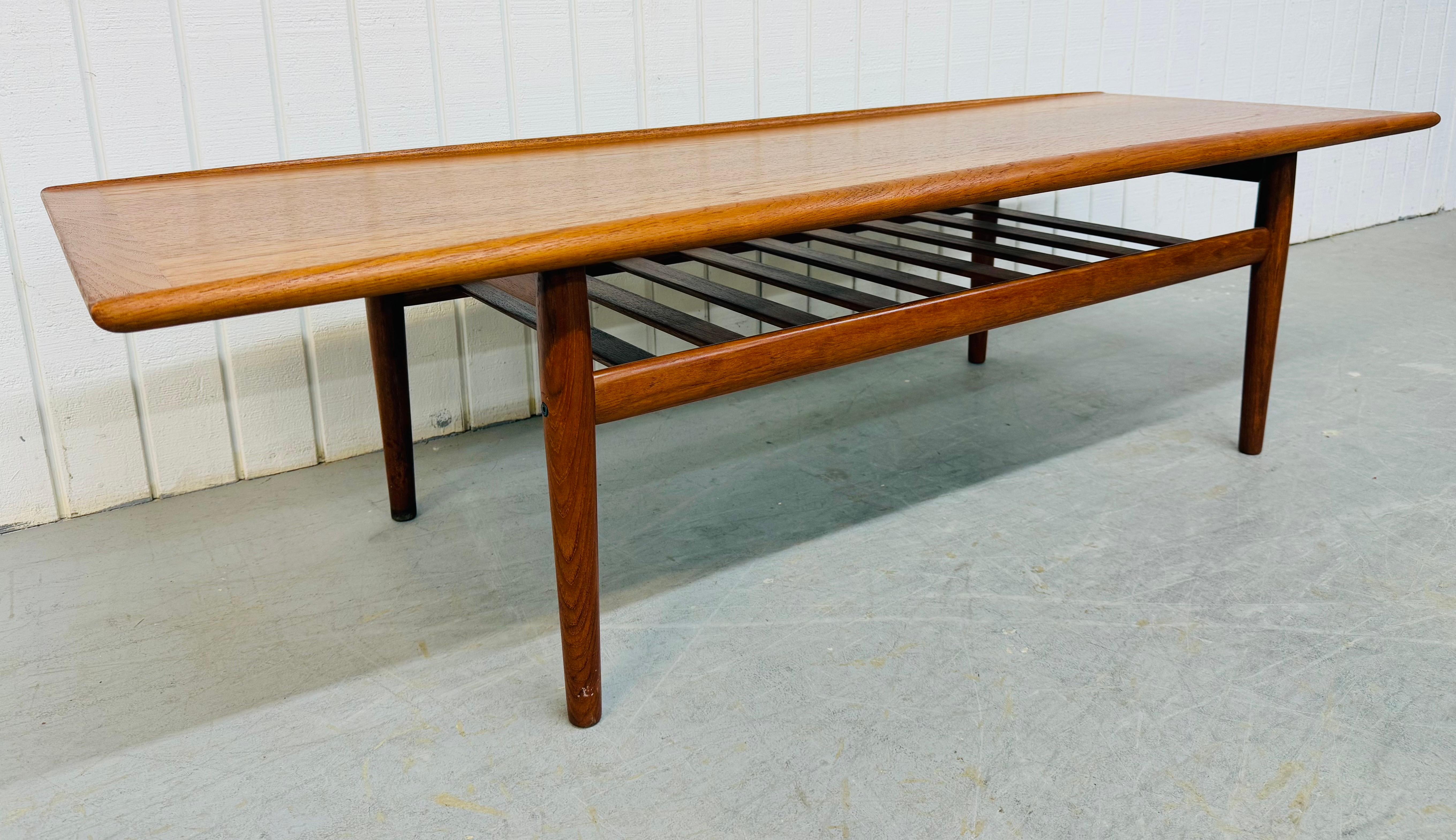 Cette annonce concerne une table basse en teck moderne danoise du milieu du siècle. Ce meuble présente un plateau rectangulaire à bord arrondi, des pieds modernes, un porte-revues en forme d'échelle et une magnifique finition en teck. Il s'agit