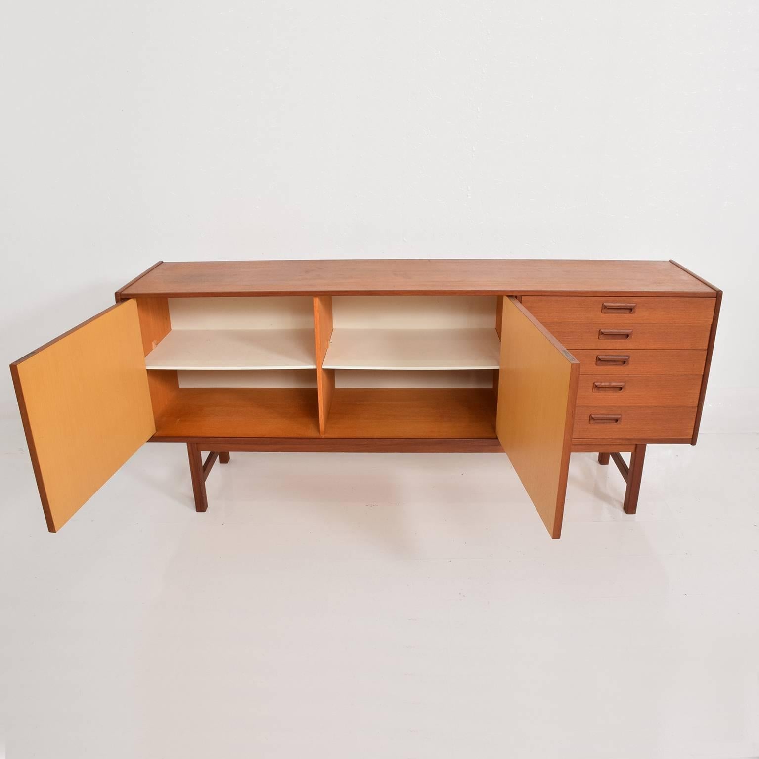 Midcentury Modern Classic Teak Credenza with two open storage areas and pull-out drawers on the left side. 
Mounted on solid teak legs.
No apparent label Piece is Unmarked. Attributed in style and design to Arne Vodder for Sibast Modern.
Denmark,