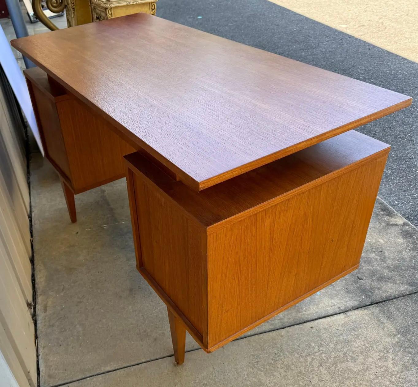 This is a mid-century Danish modern teak writing desk. It has both drawers and open space. It features the iconic floating top. It is 26” vertically for the chair. It is in very good condition. 