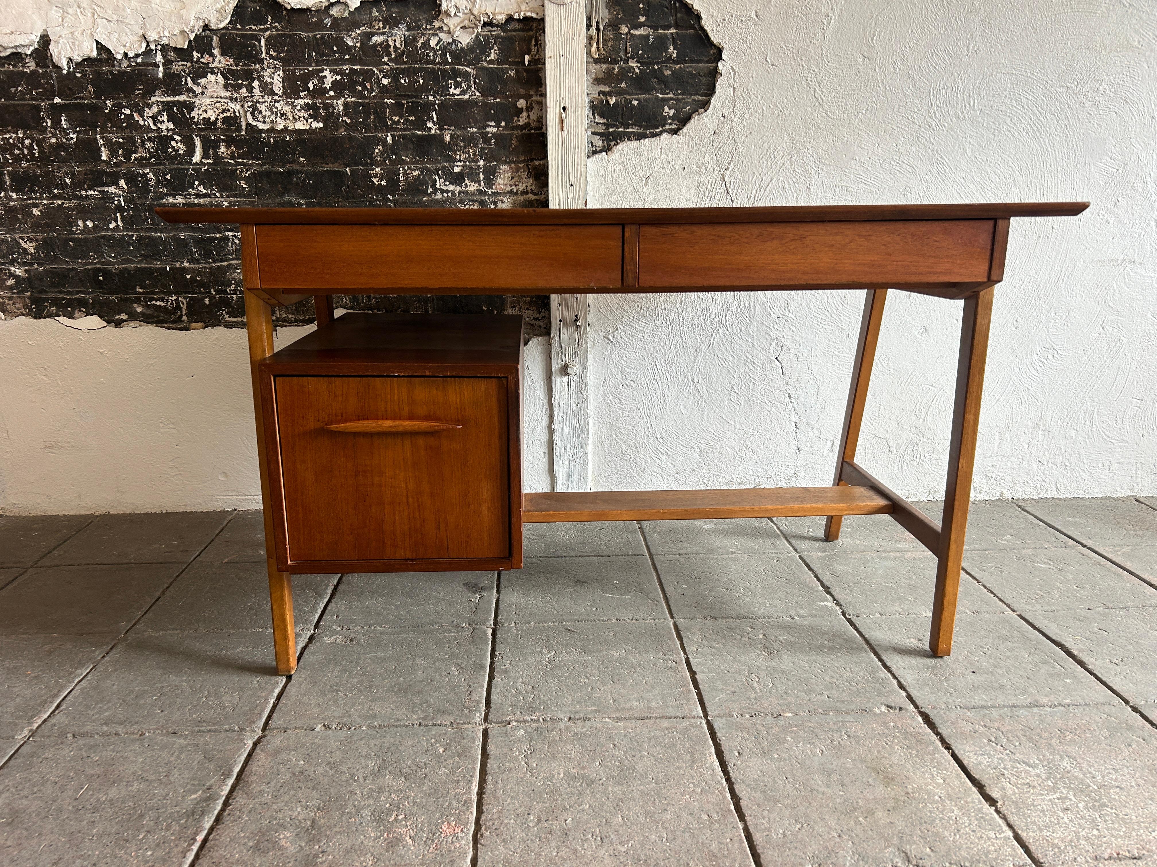 Mid century danish modern teak desk with 3 drawers And lower brace. This danish desk has (2) upper drawers and (1) lower deep file drawer. The top has a beautiful teak wood grain with the legs being a lighter oak wood as well as the lower brace.