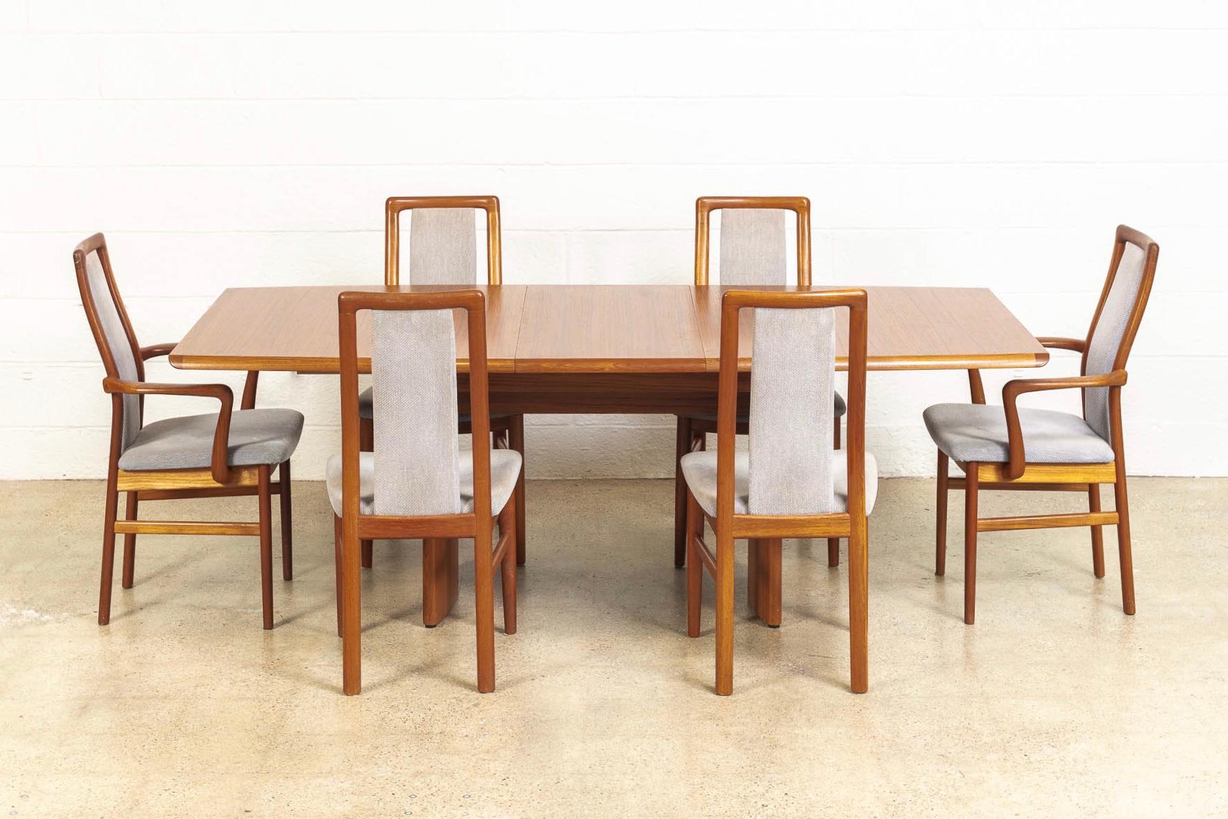This vintage Mid-century Danish modern dining set includes six teak upholstered dining chairs and a teak expandable dining table made in Denmark by Vejle Stole O.G. Moebelfabrik, circa 1960. The set has an elegant Minimalist aesthetic and a clean,