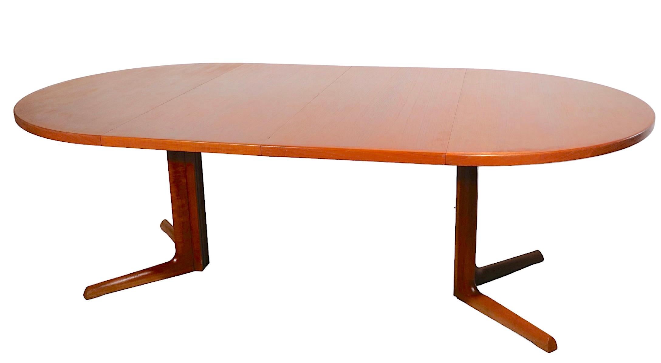 Classic Danish Mid-Century Modern dining table by Gudme Mobelfabrik, with two large leaves. The table features a split pedestal, which opens to accept the leaves, each leaf is 19 1/8 in W. Constructed of teak, this example is structurally sound and