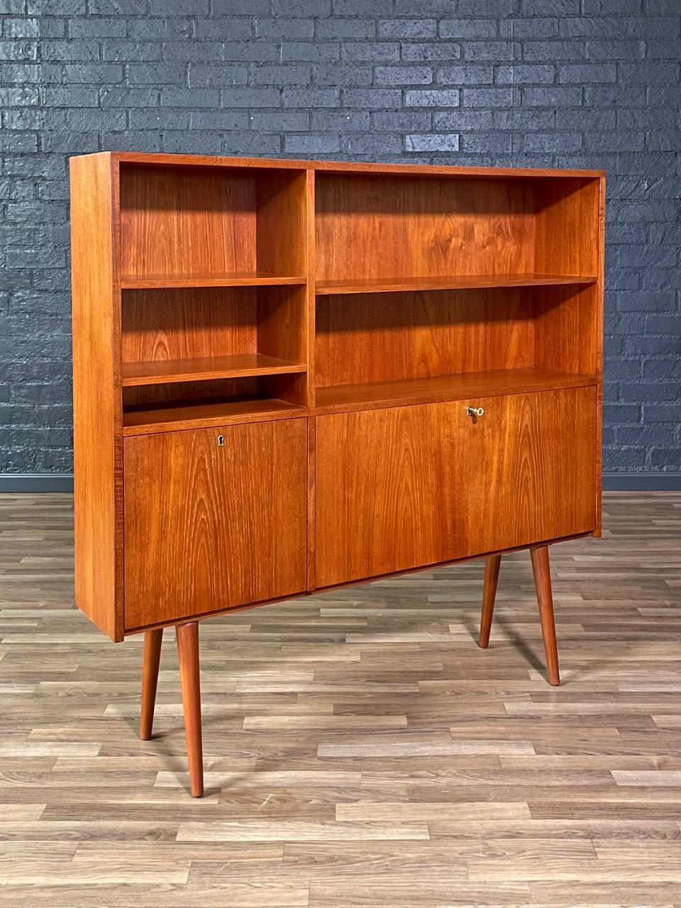 Condition: Original Vintage Condition
Materials: Teak, Original Brass Skeleton Key 
Style: Danish Modern 

This Danish Modern teak drop-down bookcase, crafted in the 1960s, is a beautiful example of mid-century functionality and design. Featuring