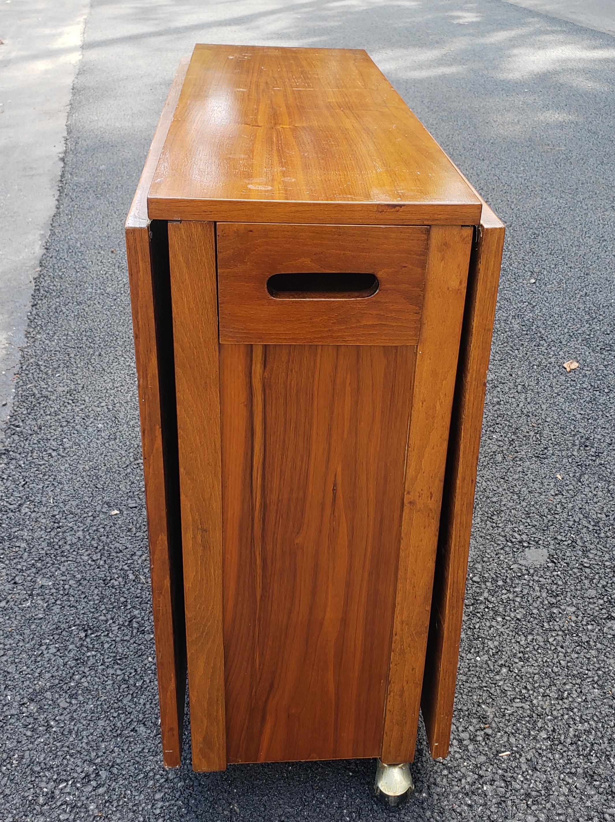 Mid-Century Danish Modern Teak Drop-Leaf Dining Table with Storage on Rollers. Leaves drop to make a compact 12.5
