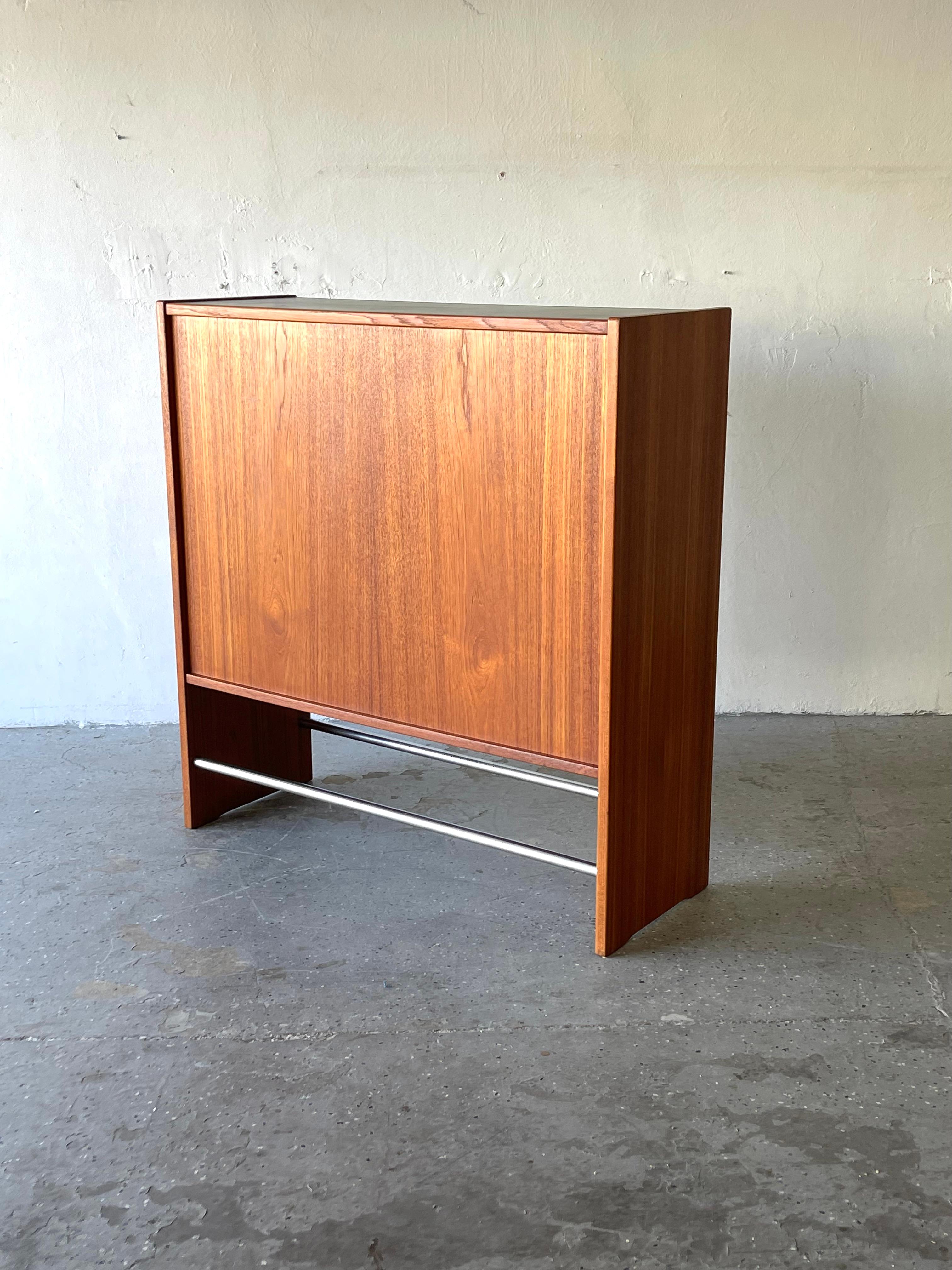 This teak danish modern dry bar by Erik Buch is Quite stunning.m Bar is in excellent vintage condition. It Has it original glass sliding doors. The black and gray round bottle housing makes a very cool contrast with the teak wood. 

Condition: