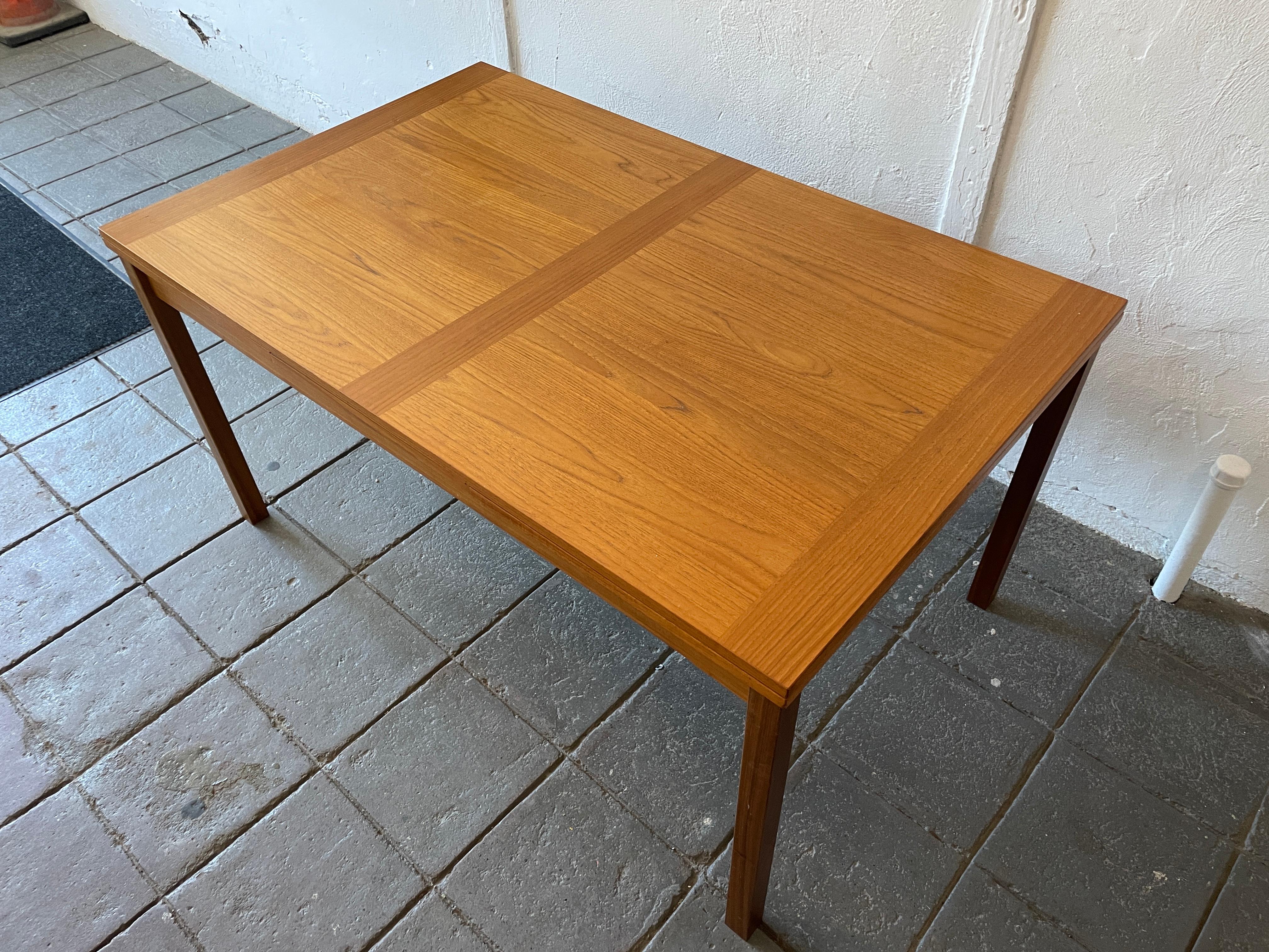 Mid century Danish modern teak extension dining table Denmark. Great Size Dining table with 2x 20” slide out hidden leaves. Rectangular design with solid teak square legs. Measures 57