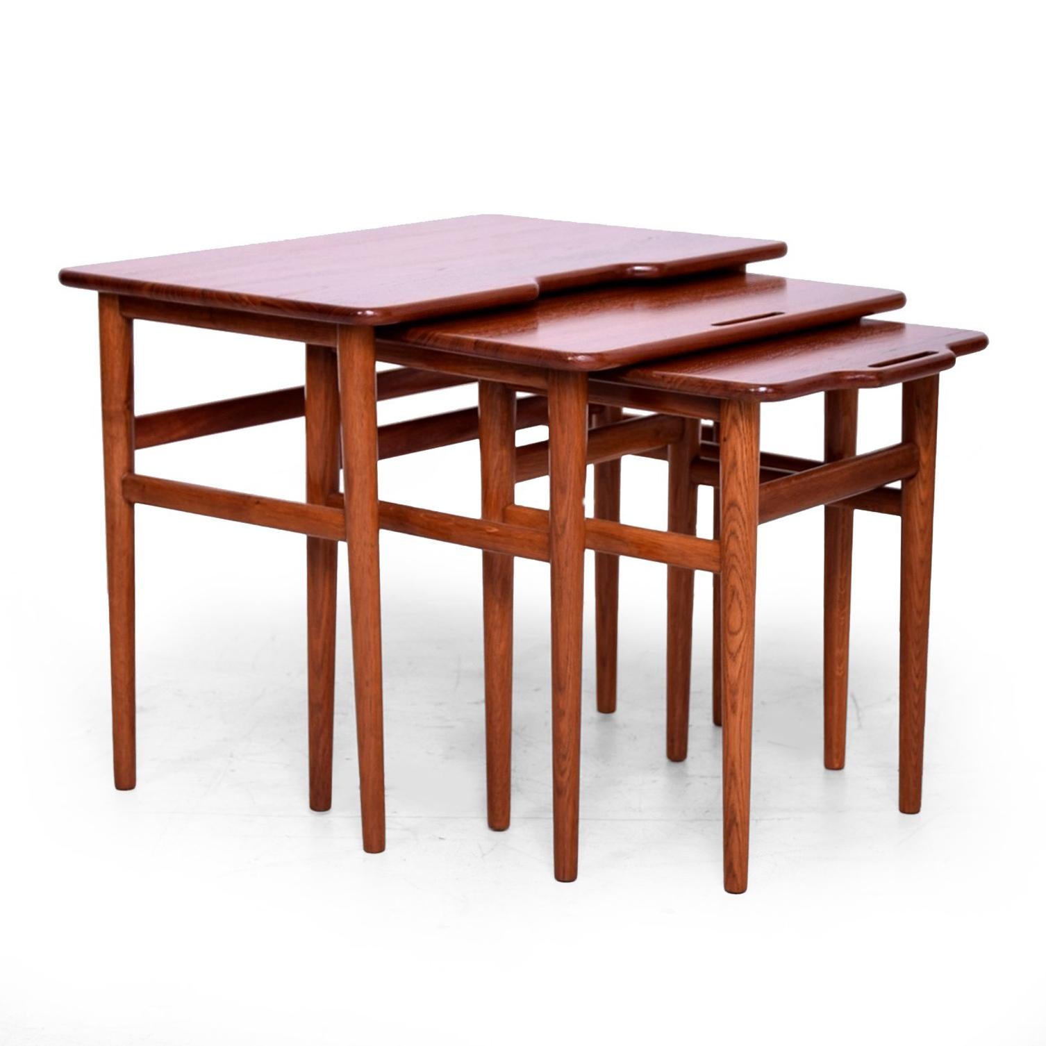 For your consideration a set of three nesting tables made of solid teakwood.

Sculptural shape with tapered legs and sculptural built in handles.

Unmarked. 
Measures: Large table: 19