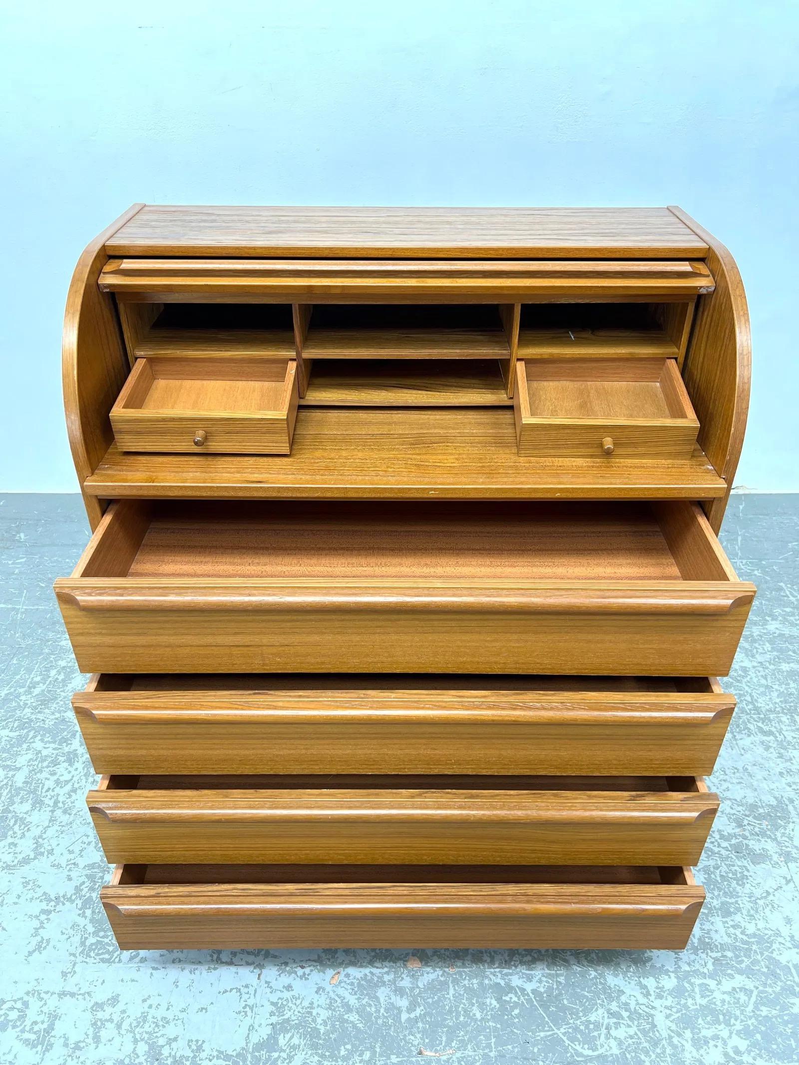 Mid-century Danish modern roll top desk crafted from teak, featuring a fitted desk compartment for organized storage. Marked GENKA Denmark, this desk showcases a sleek design that embodies the essence of Scandinavian style.

