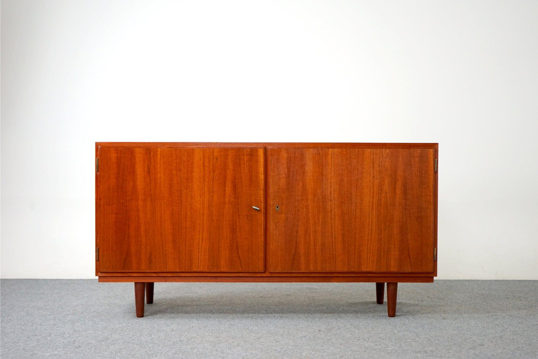 Teak Danish modern sideboard, circa 1960's. Clean, simple lined design highlights the exceptional book-matched veneer throughout. Low profile lockable cabinet offers adjustable shelving and removable legs, compact design makes it the perfect condo