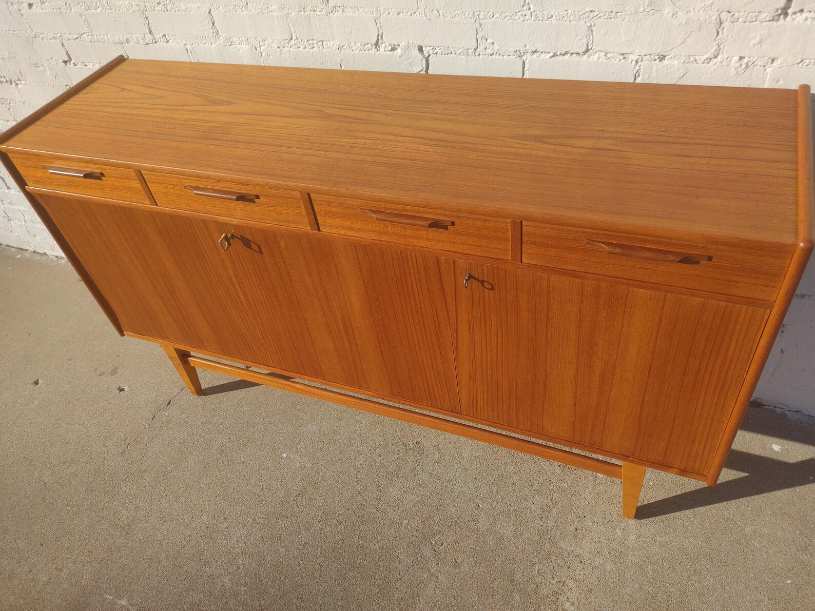 Mid Century Danish Modern Teak Sideboard

Above average vintage condition and structurally sound. Has some expected slight finish wear and scratching. Top has a couple very slight ring discolorations. Lower left side of credenza has some veneer