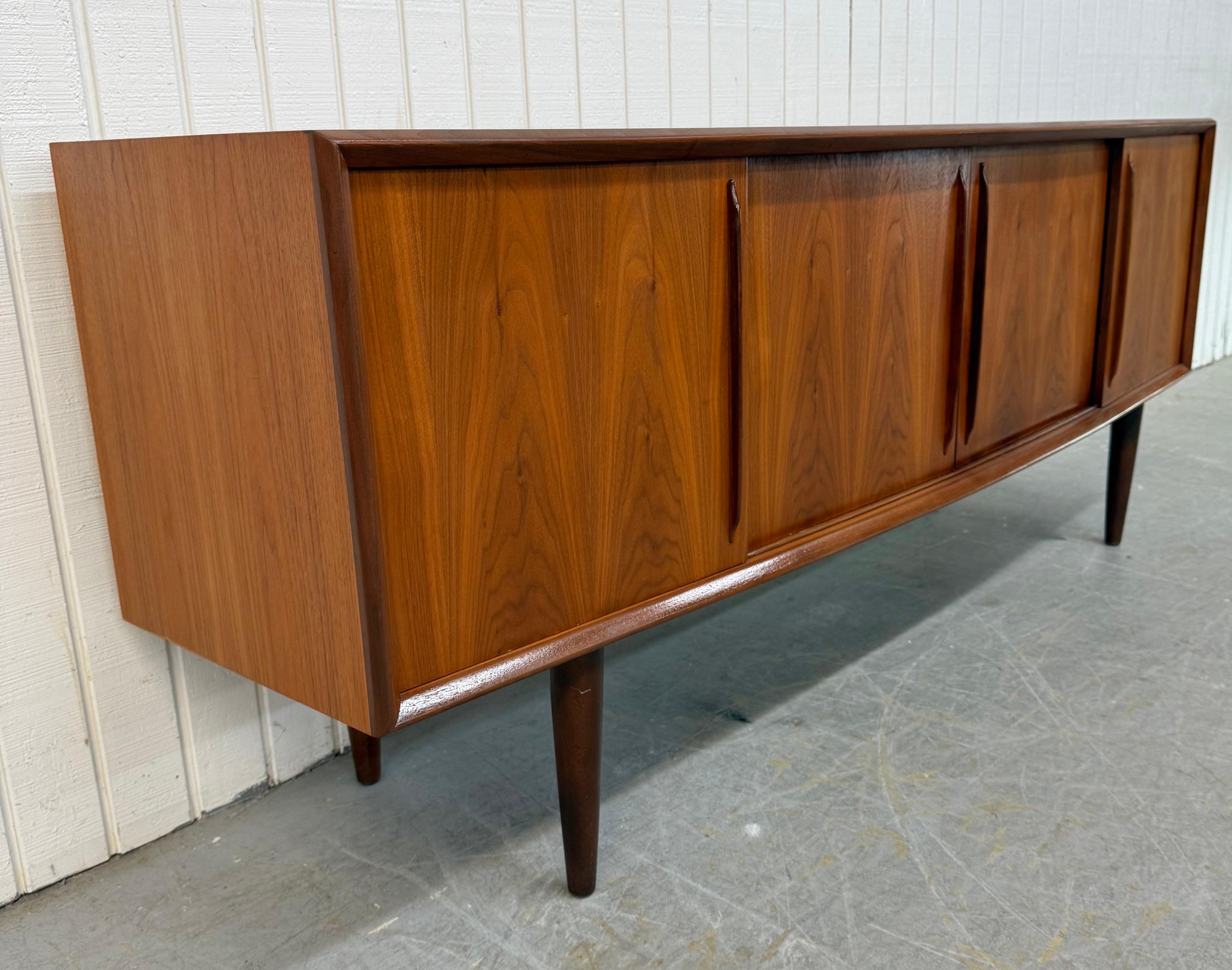 This listing is for a Mid-Century Danish Modern Teak Sliding Door Sideboard. Featuring a straight line design, long rectangular top, multiple sliding doors that open up to drawers or storage space, thick modern legs, and a beautiful teak finish.