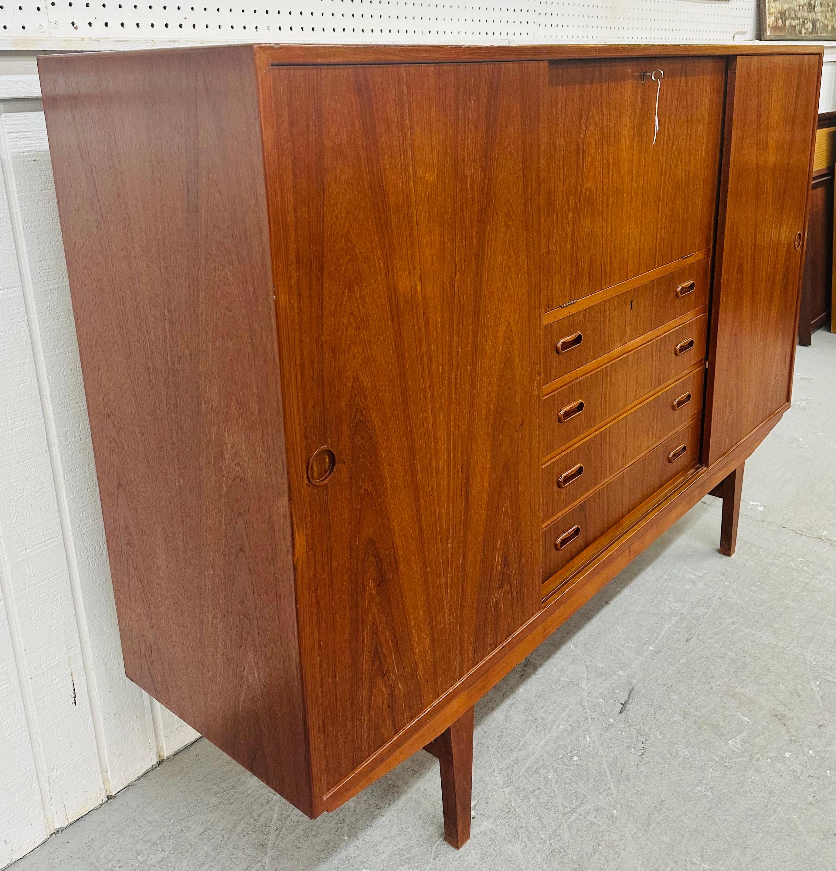 Questo annuncio si riferisce a un mobile di stoccaggio in teak danese moderno del metà del secolo. Il design è lineare, le ante scorrevoli su ogni lato rivelano uno spazio per scaffali regolabili, un'anta a ribalta con chiusura a chiave, quattro