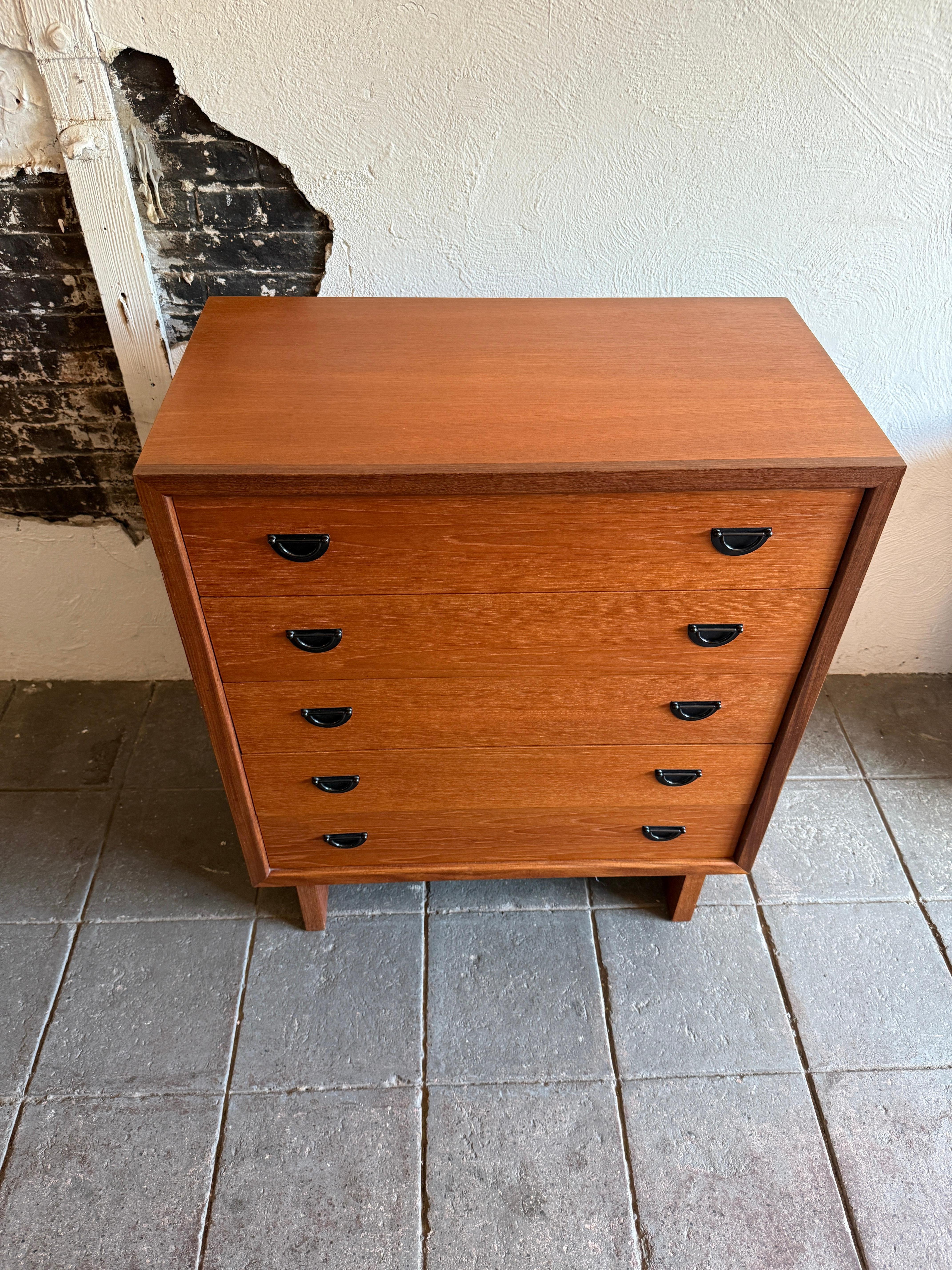 Comò alto in teak danese moderno di metà secolo con maniglie in metallo. Grande comò a 5 cassetti che poggia su 2 ampie gambe verticali. Grande design con maniglie in acciaio nero. Molto pulito dentro e fuori, pronto all'uso. 

Misura 33