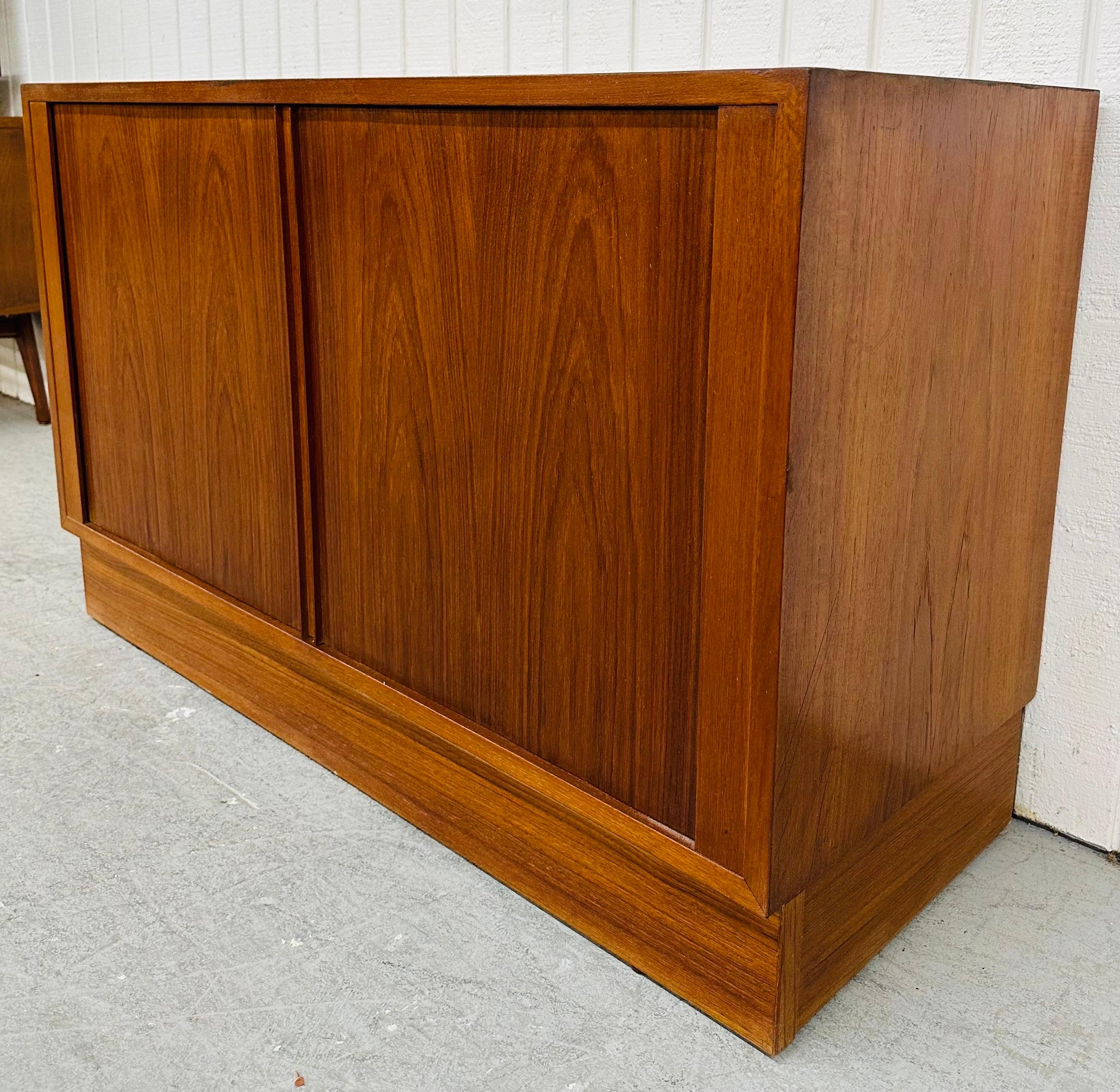 This listing is for a Mid-Century Danish Modern Teak Tambour Cabinet. Featuring a straight line design, sliding  tambour doors that open up to storage space, plinth base, and a beautiful teak finish. This is an exceptional combination of quality and