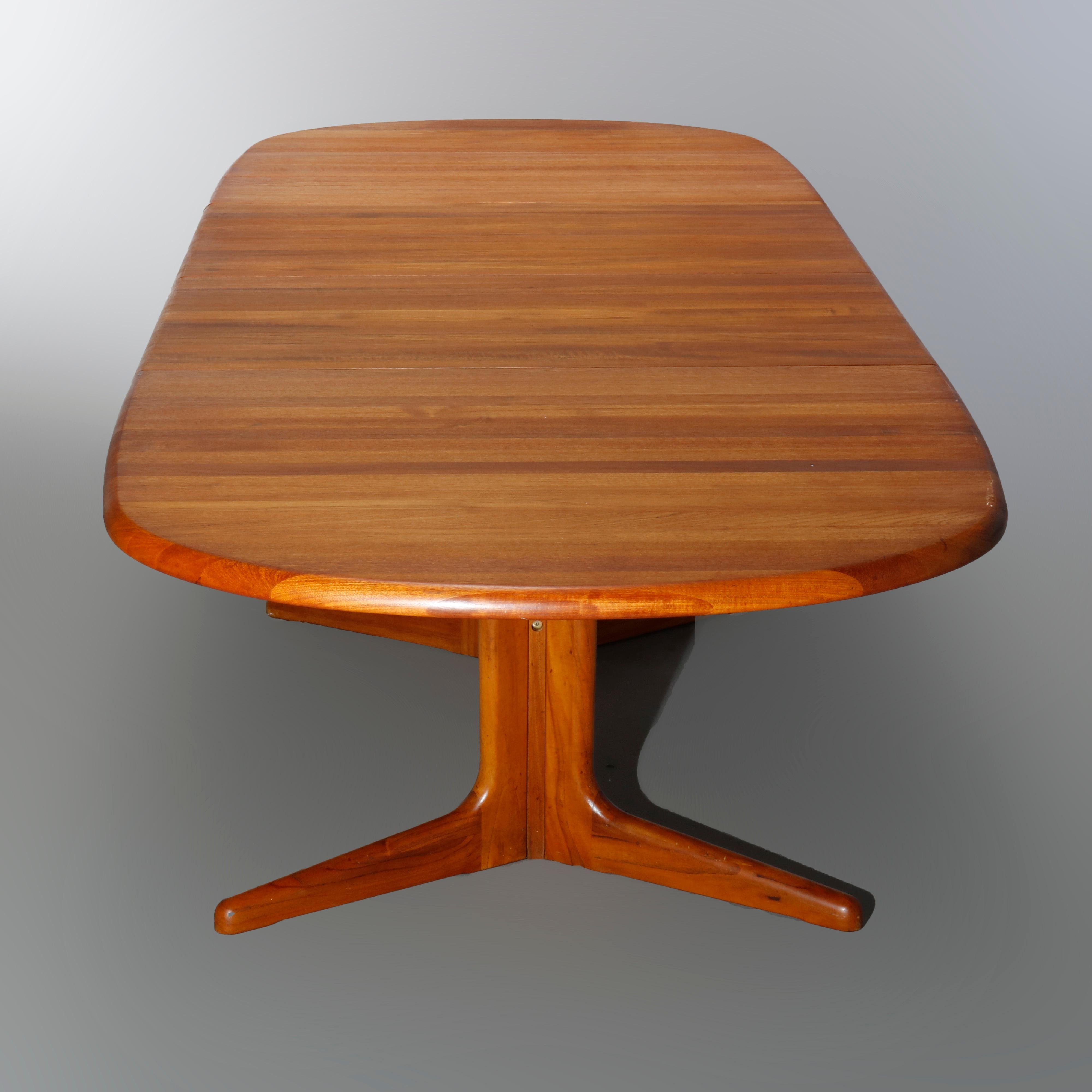 A Mid-Century Danish modern extension dining table offers teakwood construction in trestle form with v-form legs and having two 10