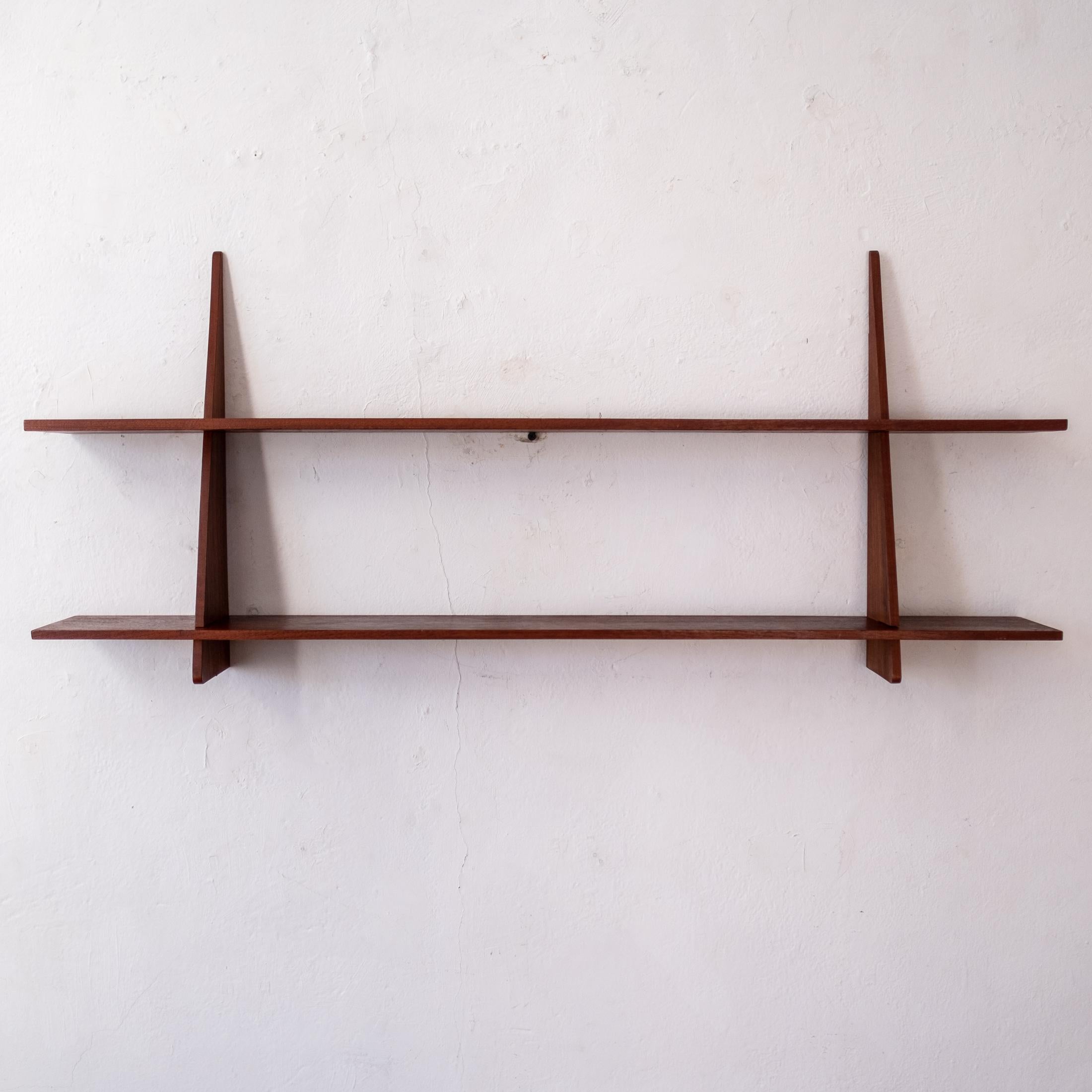 A great mid century Danish Modern solid teak wall shelf. Holes on the back of the uprights allow for the screws for mounting to be hidden. Marked Denmark. 1950s. 

Two available.