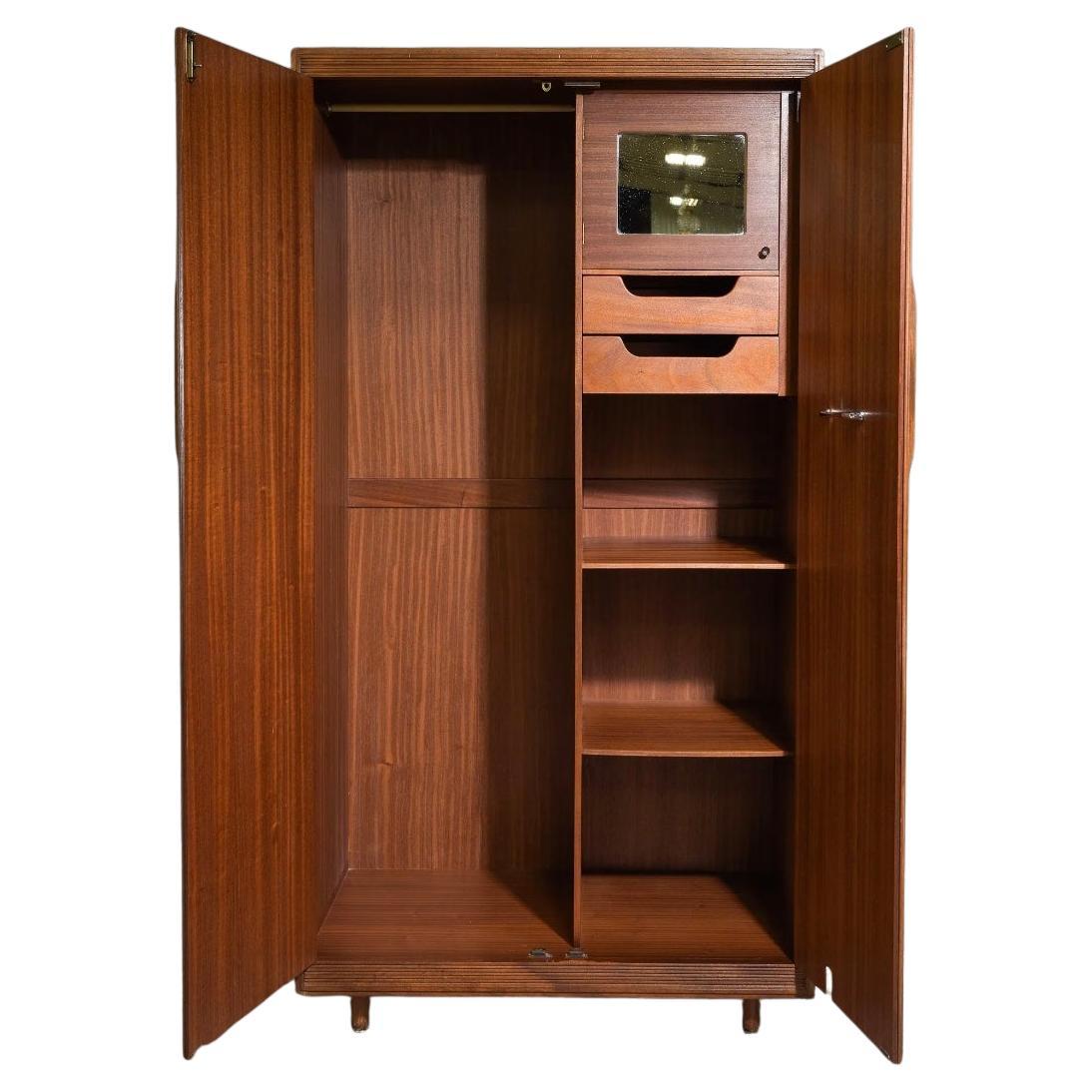 Armadio danese moderno di metà secolo in teak. Ha 2 ante frontali con 2 cassetti e ripiani inferiori e un'anta interna con specchio. L'intero interno del lato sinistro è aperto con una barra per appendere i vestiti. Ha maniglie intagliate in teak