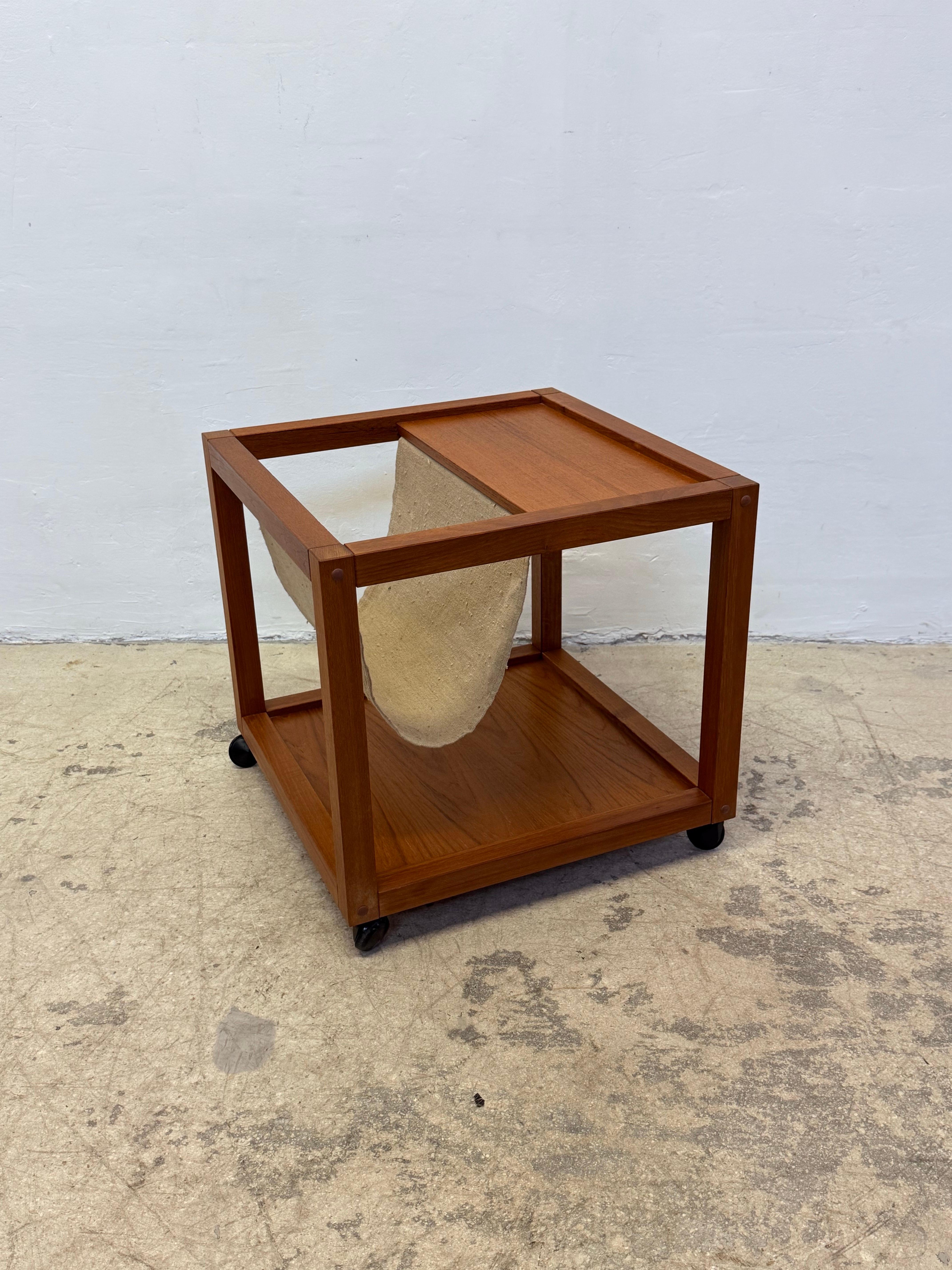 Danish modern rolling teak wood end table with canvas magazine or book holder from the 1960s.