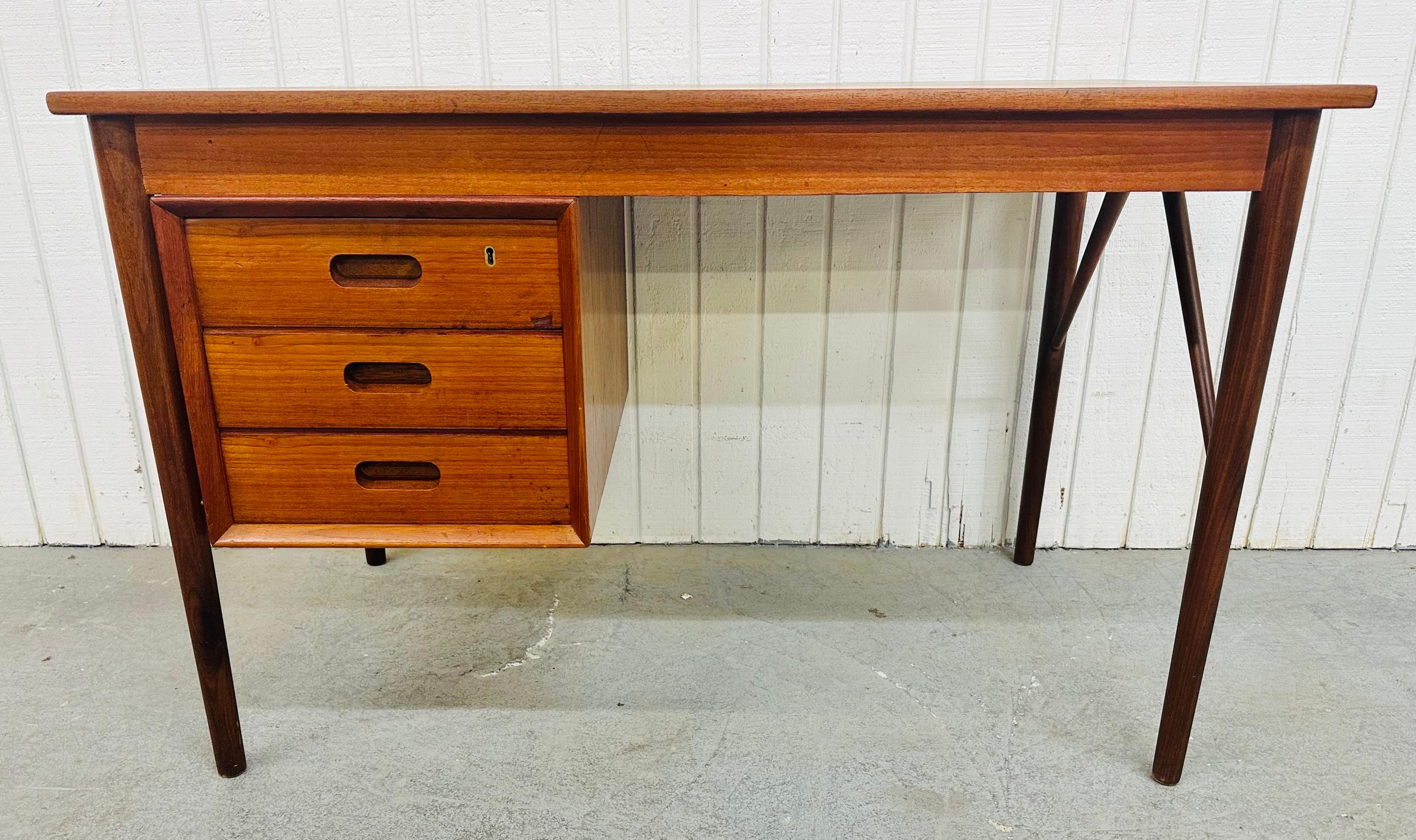 This listing is for a Mid-Century Danish Modern Teak Writing Desk. Featuring rectangular writing surface, four long skinny legs, hanging three drawer cabinet on the left side, a finished backside with storage space, and a beautiful teak finish. This