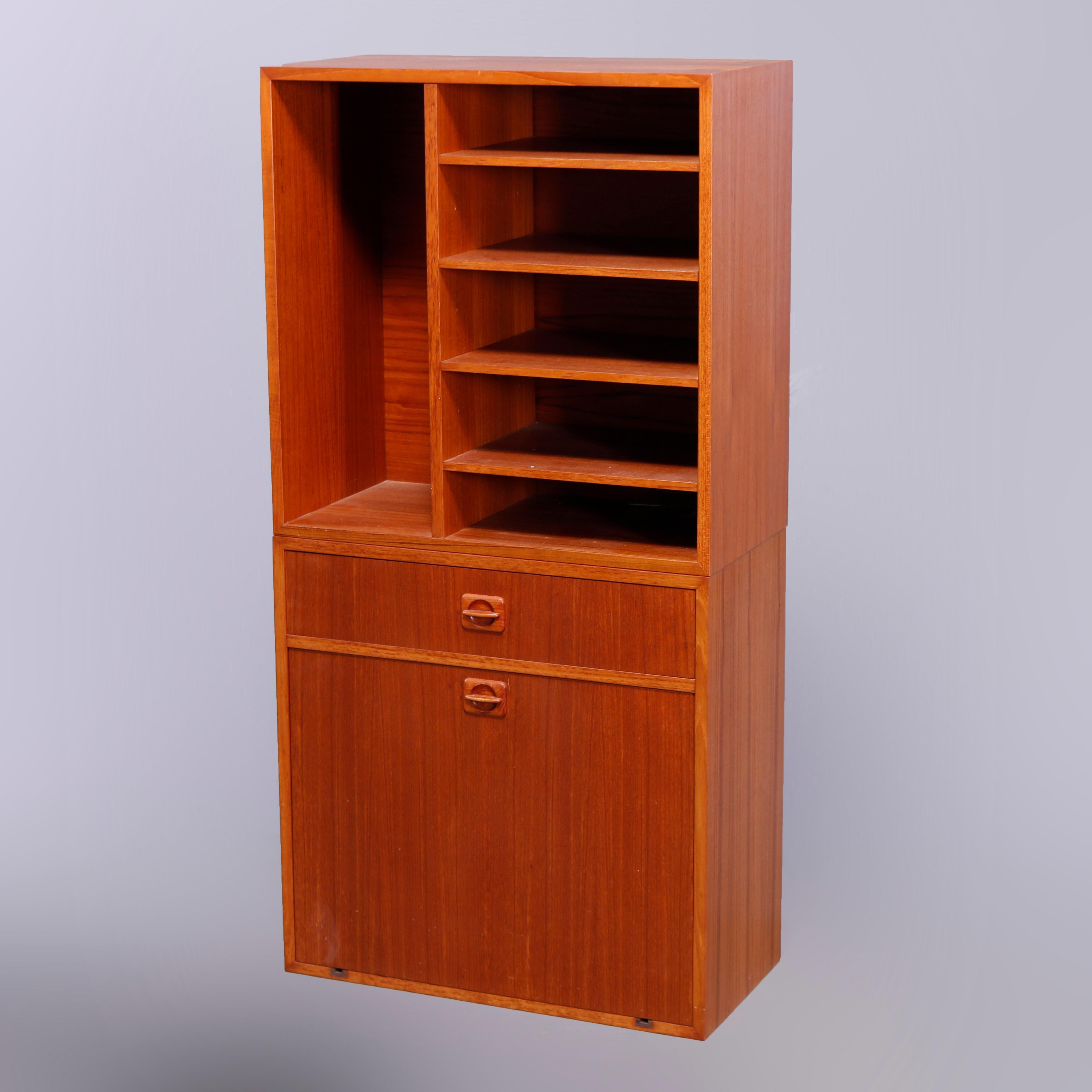 A Mid Century Modern cabinet offers teakwood construction with upper having open shelving over lower with single drawer and drop down cabinet opening to a mirrored interior, en verso Made in Denmark label, c1960

Measures - overall 47.5''H x