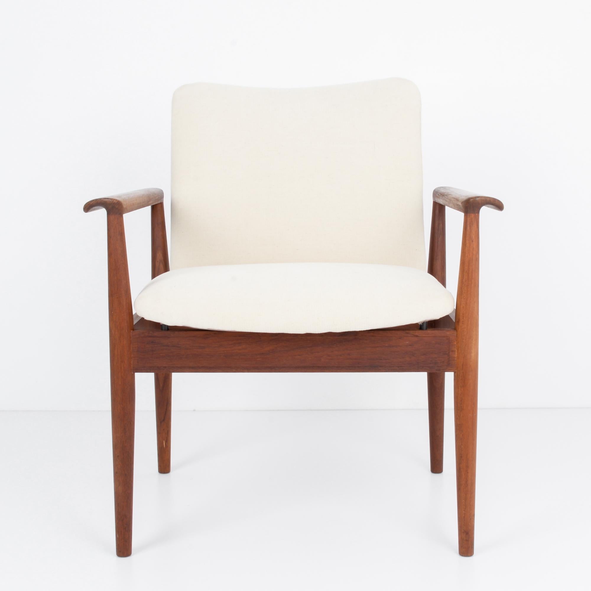 A wooden armchair from Denmark with upholstered seat and back, circa 1960. A chic seat, perfectly calibrated to facilitate conversation and silent contemplation, following design principles of Scandinavian Modernism. Timeless and sophisticated, this