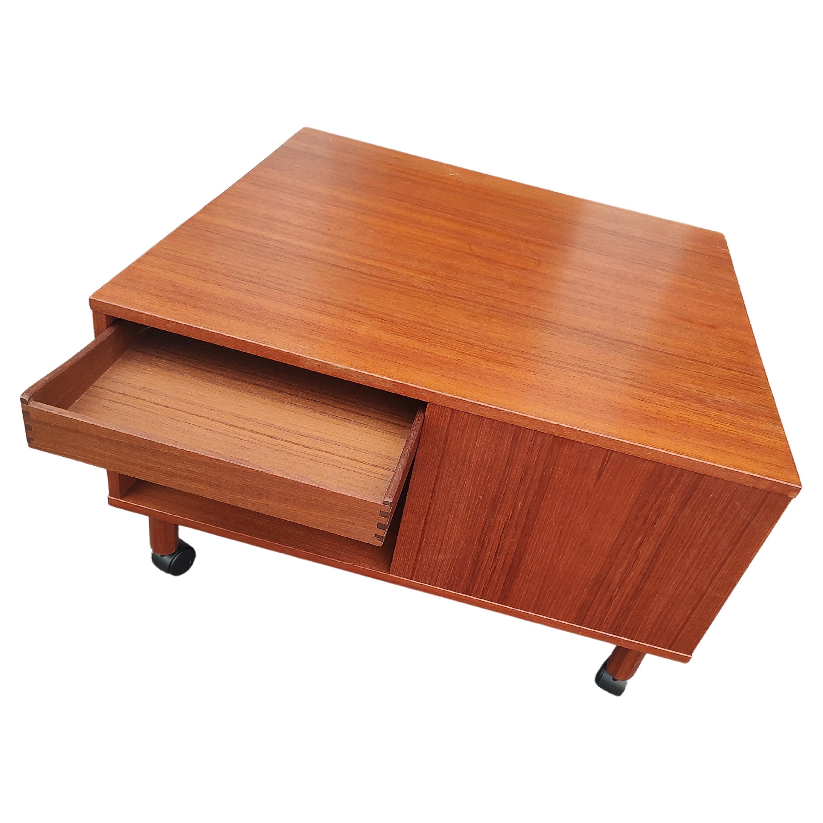 Fabulous and versatile teak cocktail table with a drawer on one side a cutting board on another side a pullout writing slot and a magazine rack on the last side. All functional viable accessories to accommodate your needs. In excellent vintage
