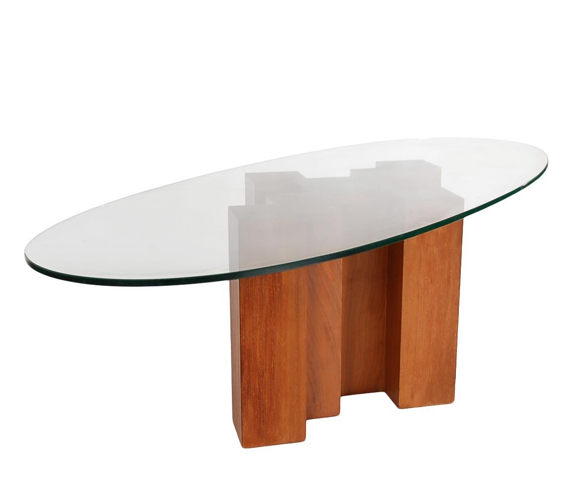 An unusual form walnut base coffee table in the style of Adrian Pearsall. It features a walnut cubist style base, with elongated clear oval glass top. Clean and ready to use condition.