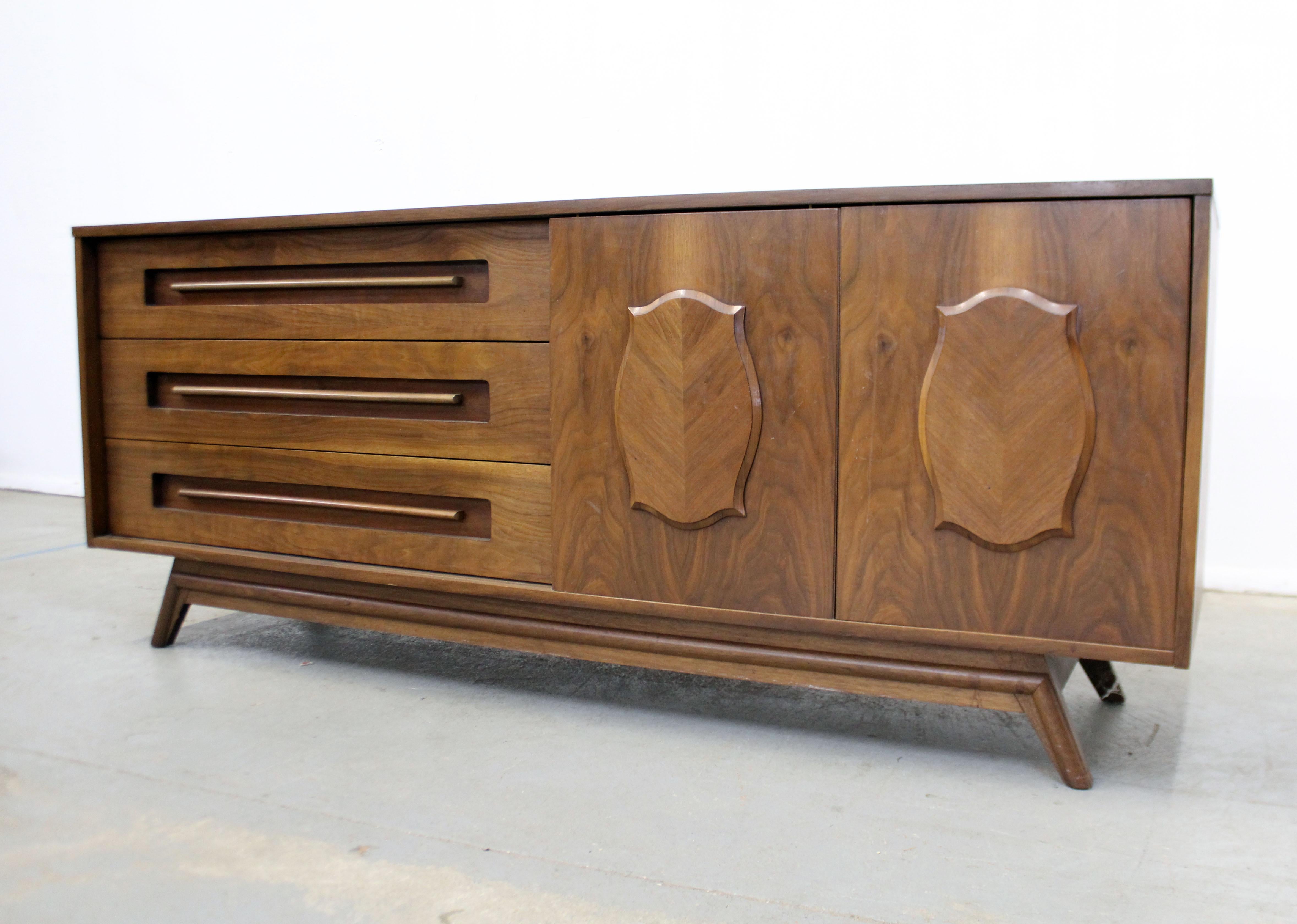 Offered is an exceptional mid-century modern credenza sure to impress anyone who sees it. It is made of walnut, featuring 2 parqueted sliding doors with 9 drawers. It is in good vintage condition, showing some wear, including surface scratches,