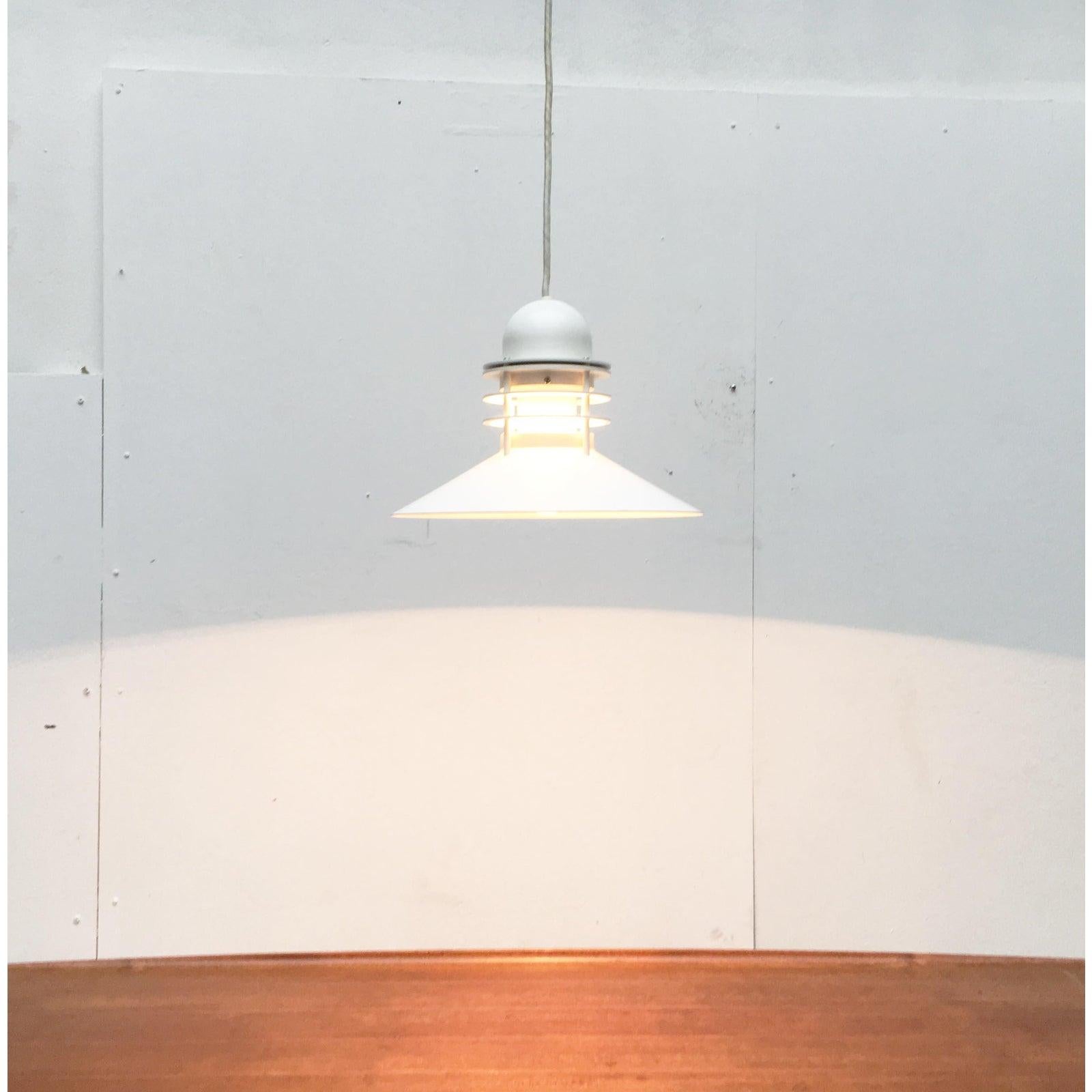 Nyhavn pendant from the Danish manufacturer Poulsen after a design by Alfred Homann and Ole V. Kjær from the 70s.

Particularly striking is the flat shade, which ensures a particularly wide radiation of light downwards. The lamp body closes off