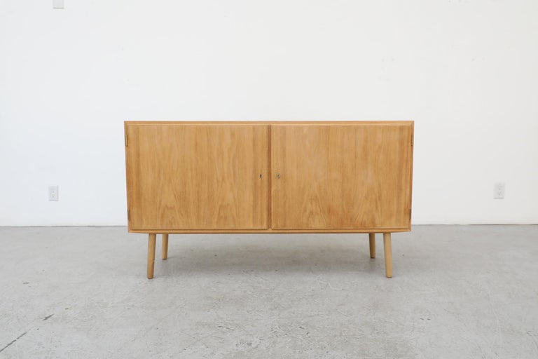Omann Jun Møbelfabrik, a family owned company designed that crafted some of the most premium mid century Scandinavian furniture of the era produced this Mid-Century oak cabinet credenza with locking doors, shelves and two small drawers inside. In