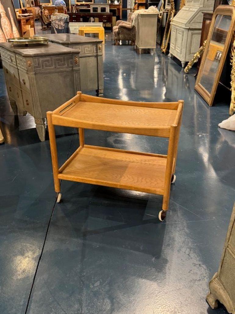 Crafted with the timeless elegance of Danish design, this mid-century serving cart by Hans Wegner is a stunning piece of furniture that blends functionality with sculptural beauty. The cart is made from rich, warm oak, that showcase Wegner's