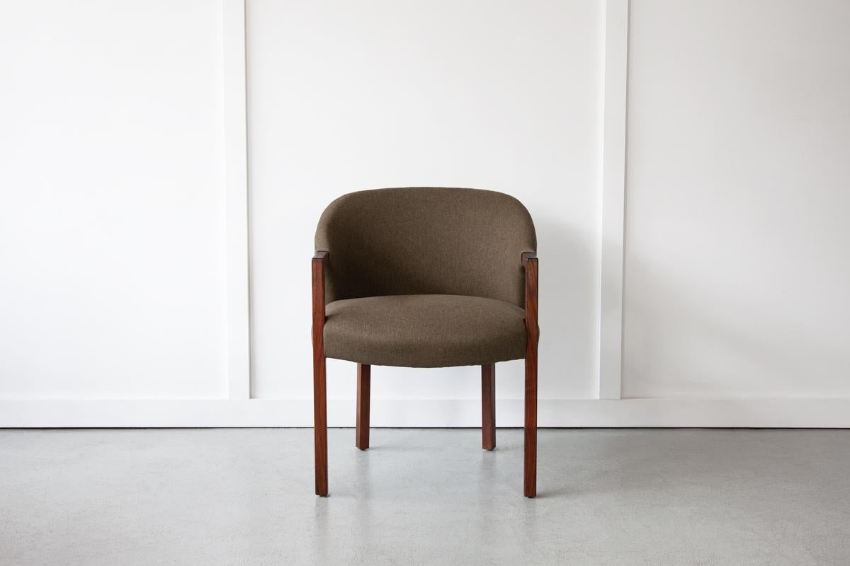 A beautifully minimalist Danish occasional chair with a welcoming curved back that contrasts wonderfully with the clean, straight lines of the rosewood armrests and legs. Newly upholstered in a 'Forest Green' contract use fabric.