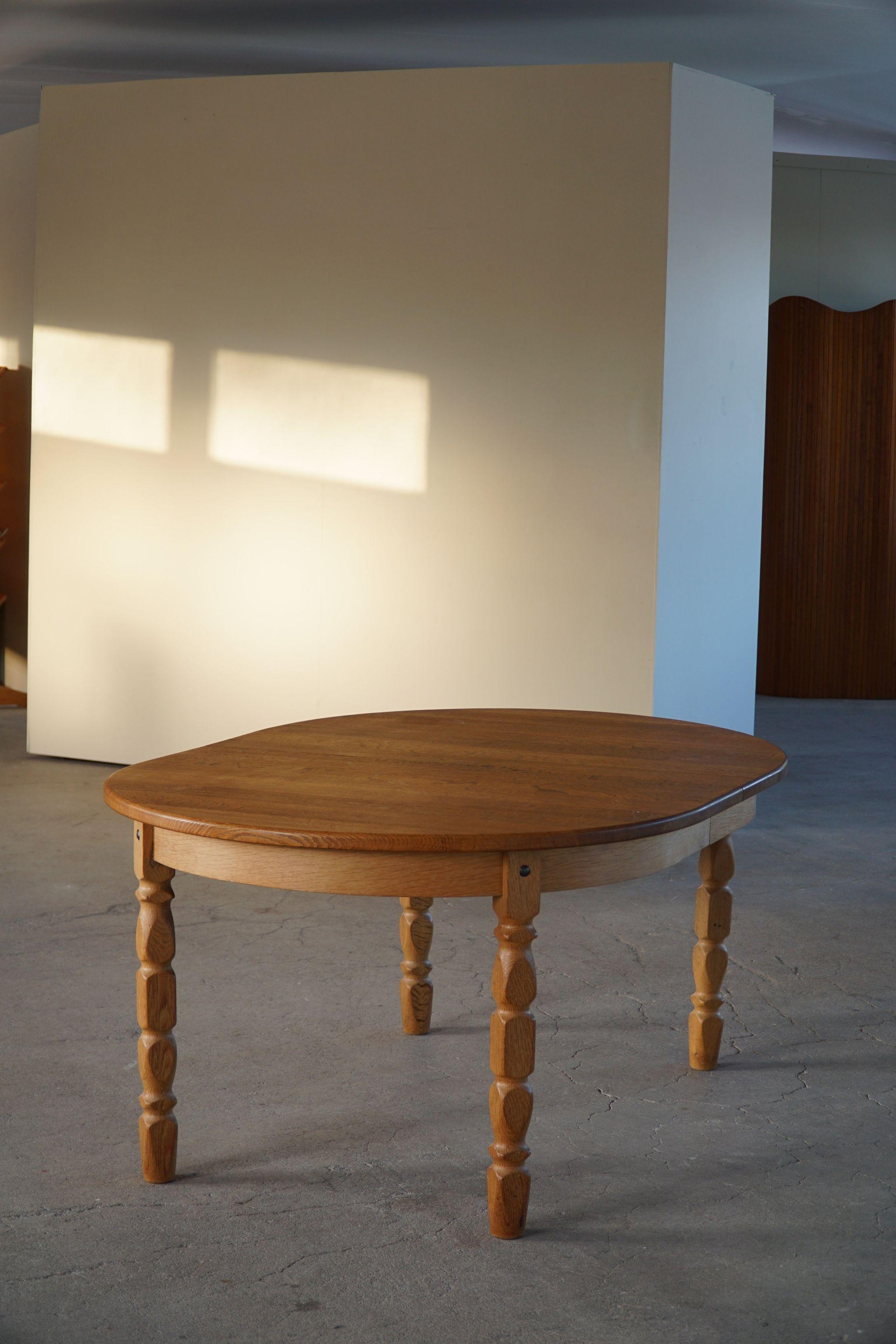 Sculptural oval dining table in solid oak with one extension, made in 1960s by a Danish Cabinetmaker. Attributed to Danish architect Henning Kjærnulf for Nyrup Møbelfabrik. 

Curved legs and great craftmanship in this brutalist table. 
Light signs
